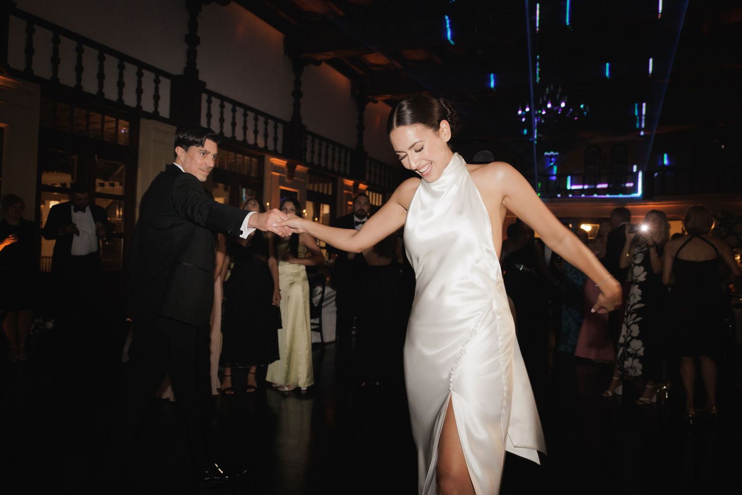 A couple dancing together on a dark dance floor in an intimate ballroom setting.