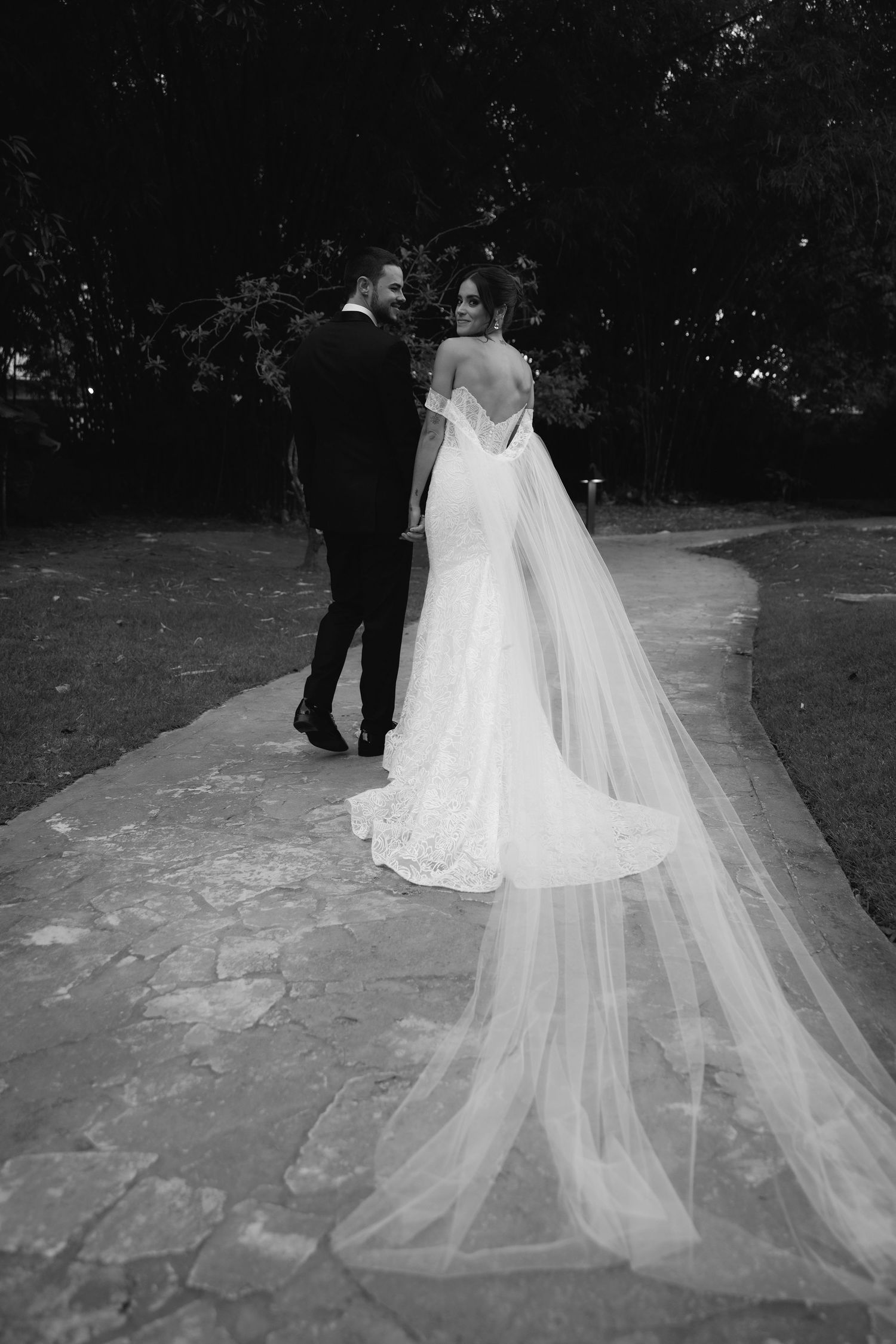 Black and white wedding photograph showing a flowing cathedral-length veil trailing behind a bride's white gown.