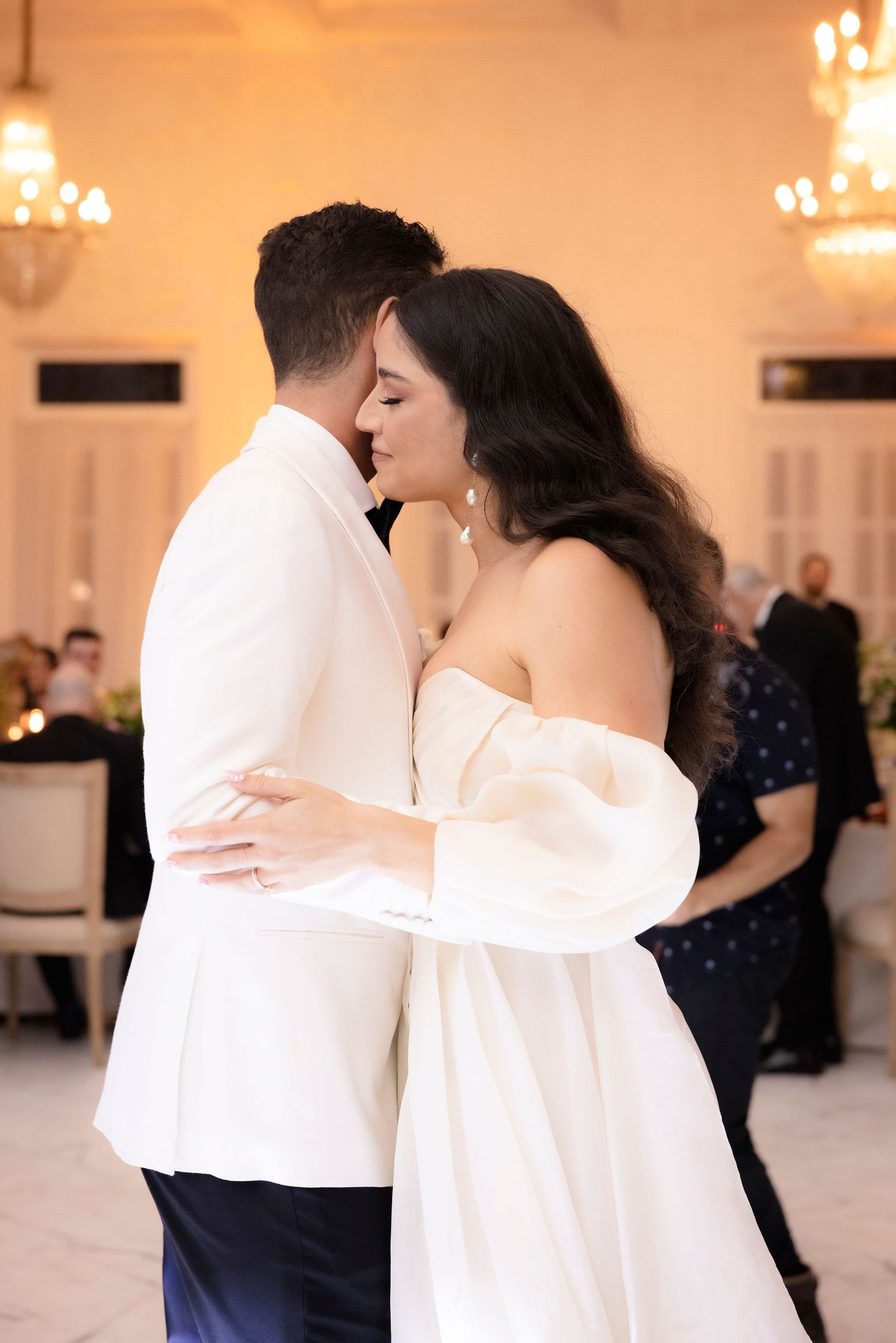Couple dancing in formal attire at an elegant reception venue.