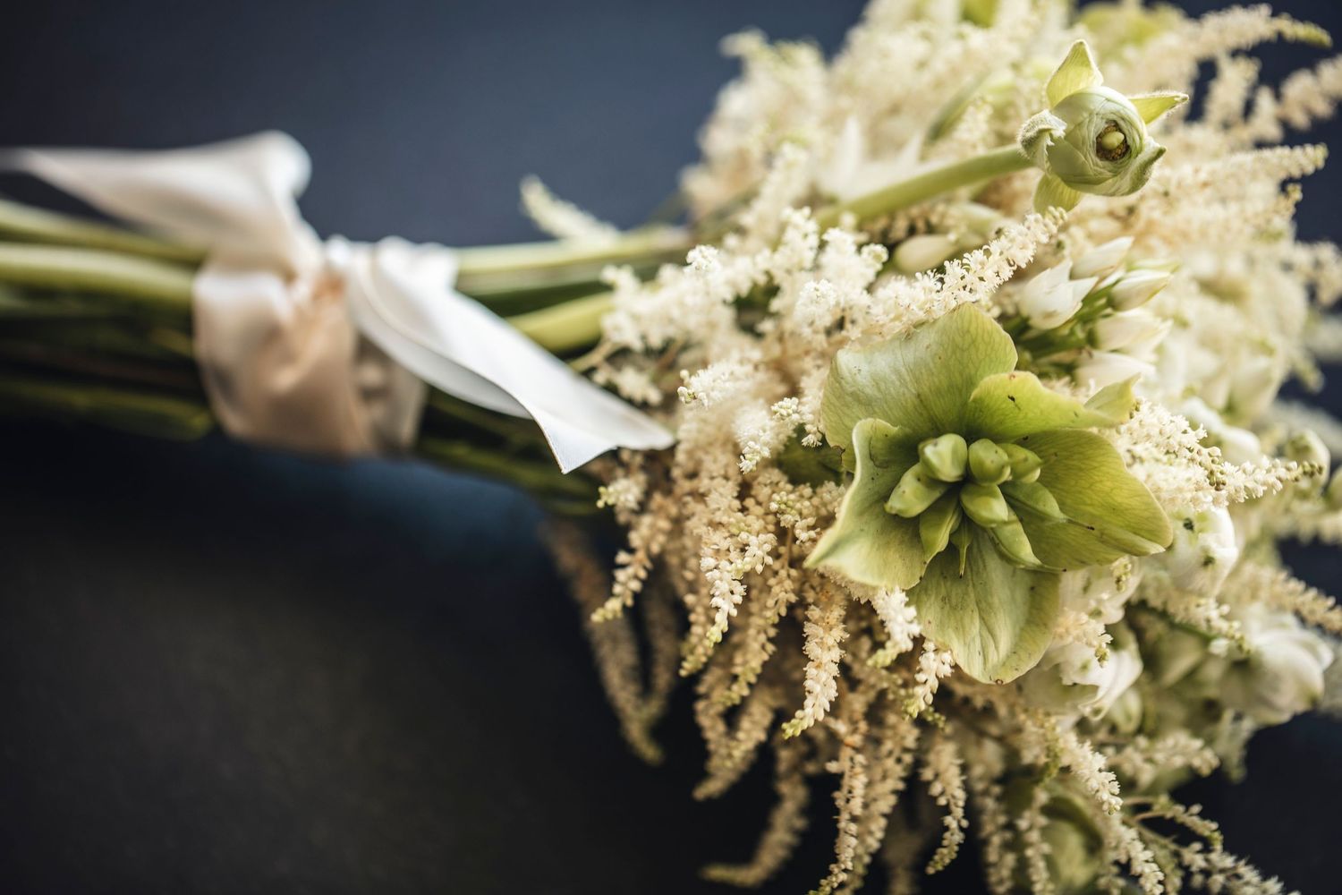 A collection of elegant white anemone flowers with black centers arranged as boutonnières with greenery and ribbons.