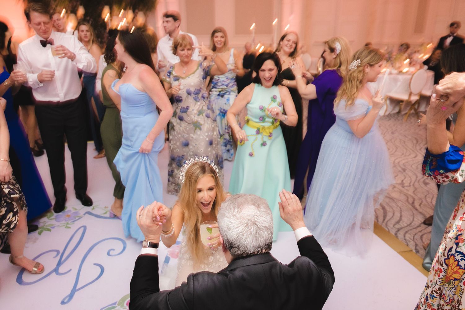 Wedding guests in formal attire enjoying festivities on an illuminated dance floor.