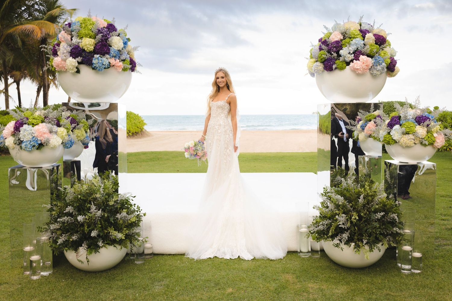 Wedding decor at an outdoor venue featuring elegant white floral arrangements in modern spherical vases.