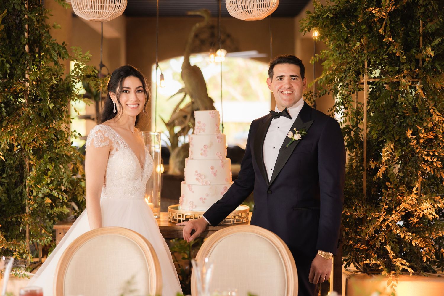 Wedding reception venue decorated with hanging lanterns and lush greenery creates romantic ambiance.