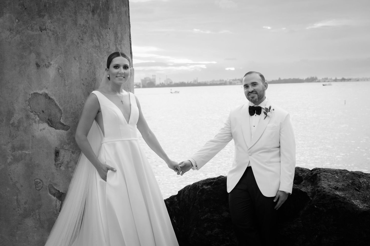 Panoramic wedding photos capturing romantic moments along a coastal fortress wall.