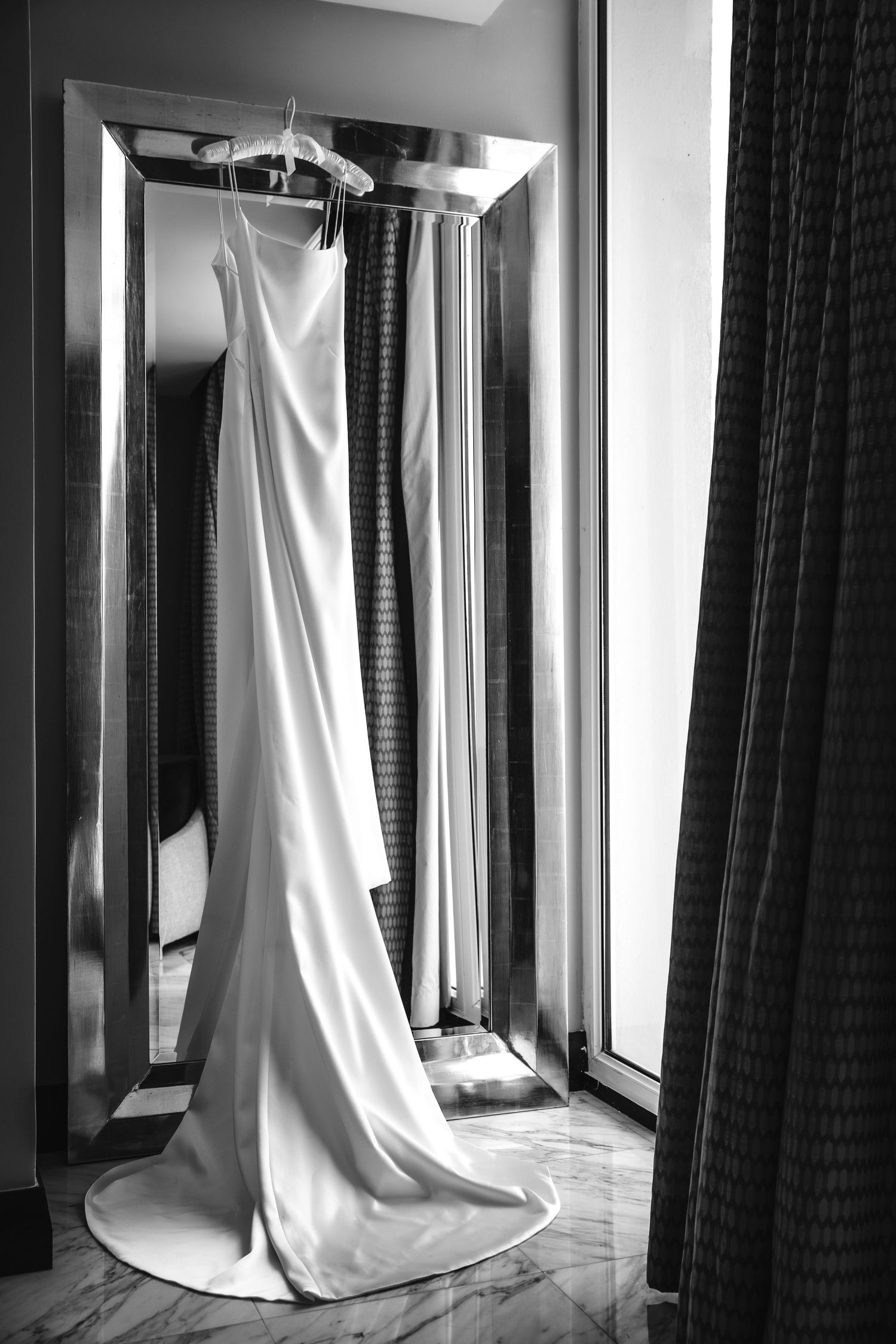 Artistic black and white composition of long flowing white curtains in a hallway with dramatic lighting.