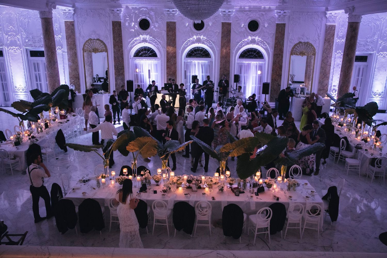 Wedding reception hall decorated with elegant round tables, white linens, and ambient lighting creating a romantic atmosphere.