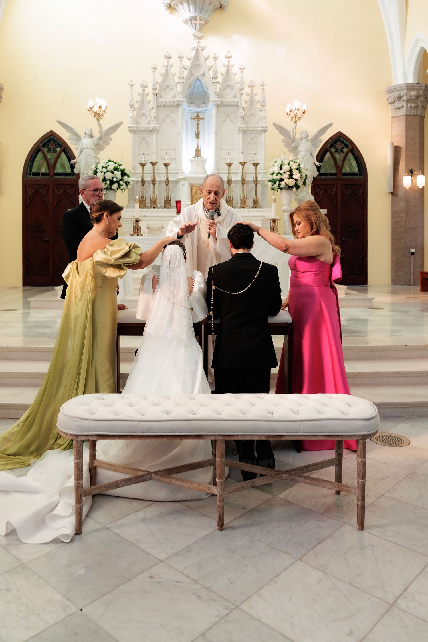 A wedding ceremony takes place in an ornate church with gothic arches and a decorative altar.