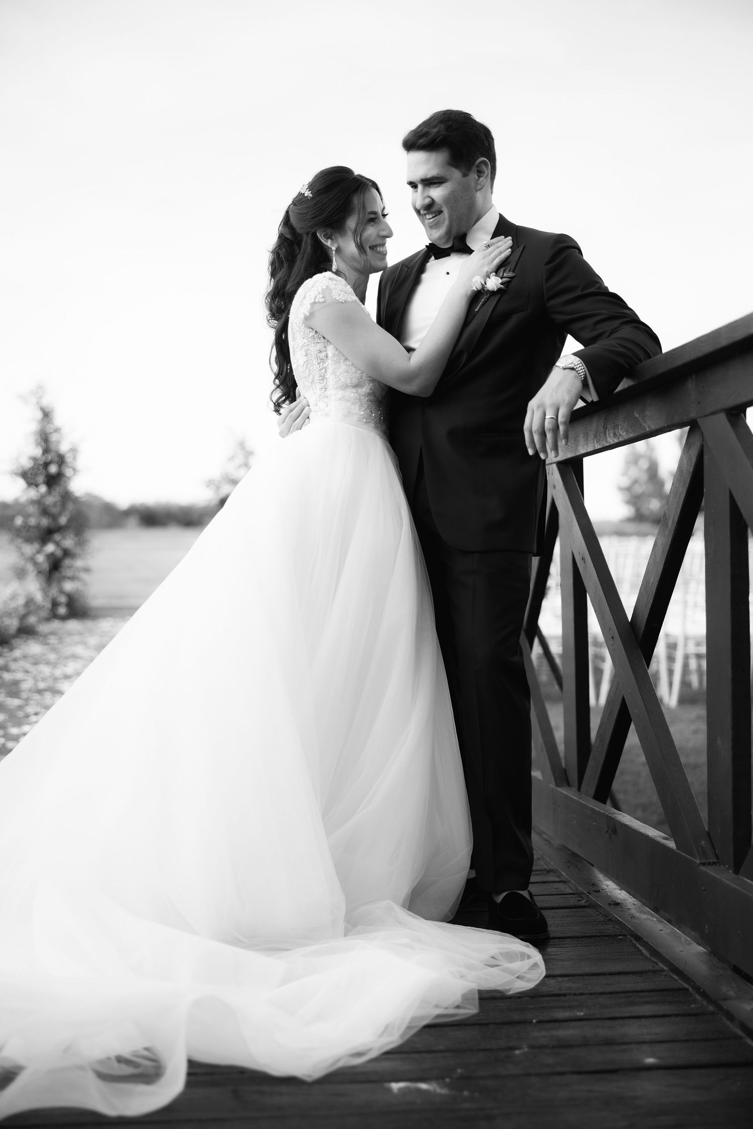 Black and white photos capture tender moments between newlyweds on a wooden bridge.