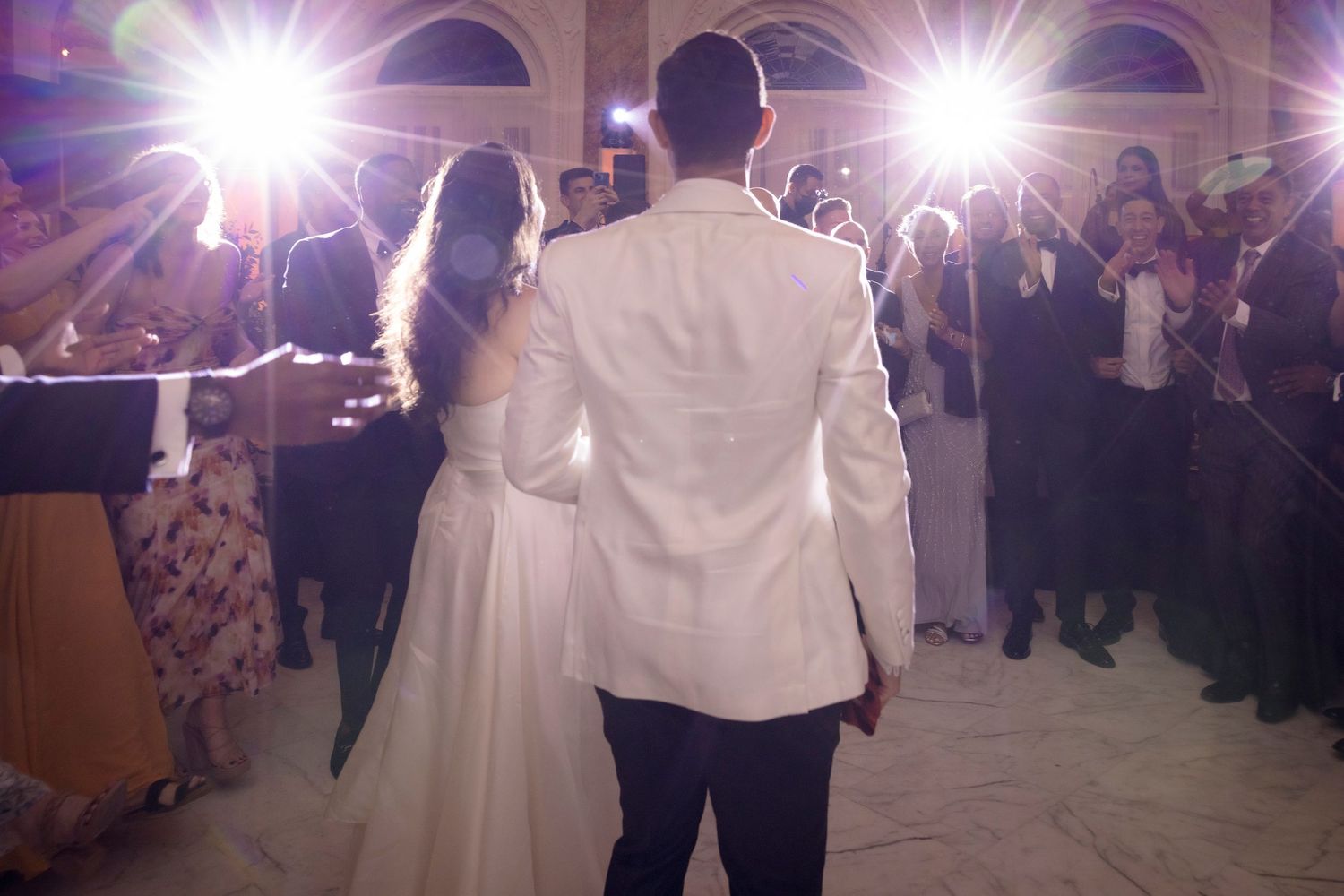 A couple shares their first dance during a wedding reception highlighted by bright ballroom lighting.