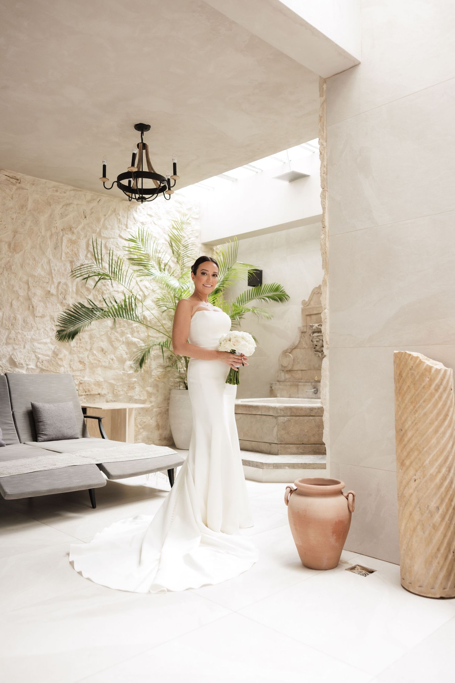 A light and airy white-walled space with stone accents and potted palms creates an elegant bridal preparation area.