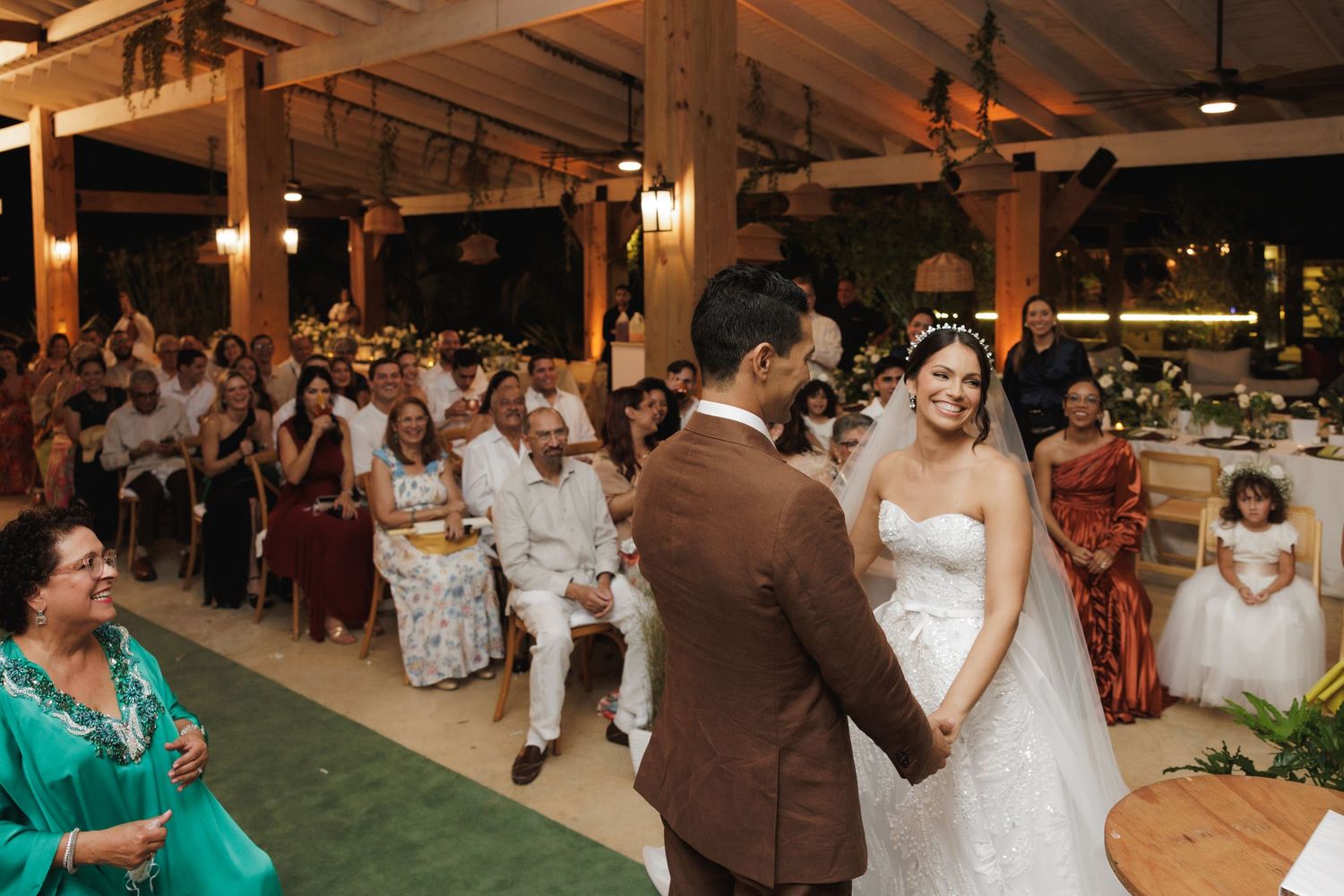 Couple dancing at their wedding reception in a rustic venue with wooden beams and guests watching.