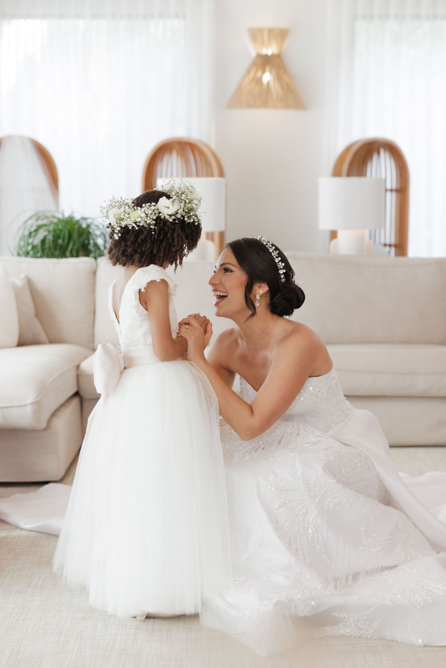 Wedding party in white dresses poses playfully in a bright modern room.