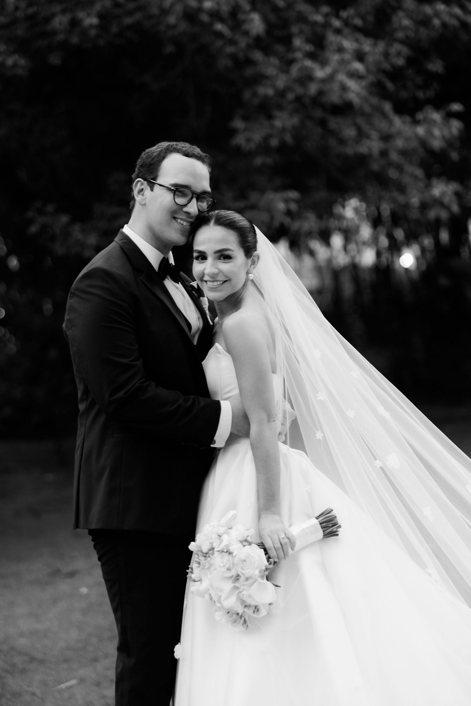 Black and white romantic wedding photos show a couple sharing intimate moments outdoors in a garden setting.