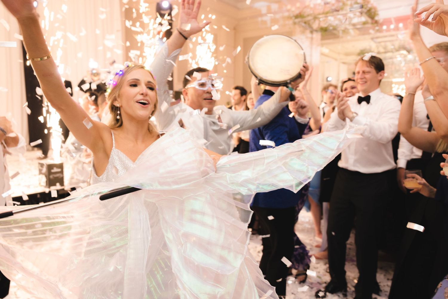 A wedding celebration features dancing and confetti in a reception hall with a joyful atmosphere.