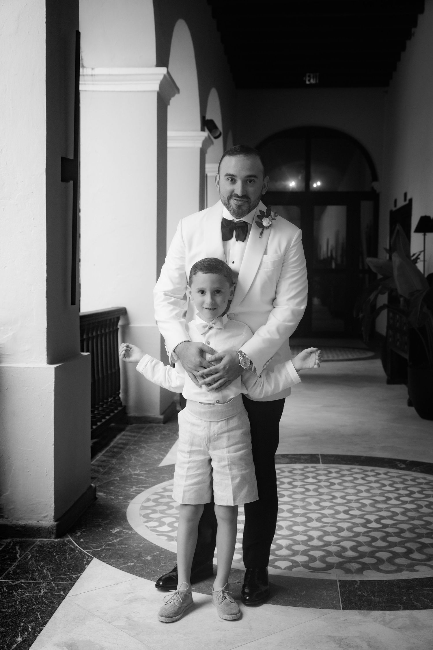 Black and white photos of a toddler with an adult in formal wear walking through a hallway.
