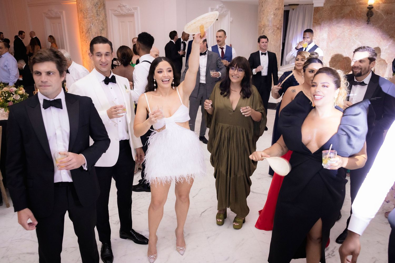 Wedding reception guests dance together on a crowded dance floor at an elegant venue with ambient lighting.