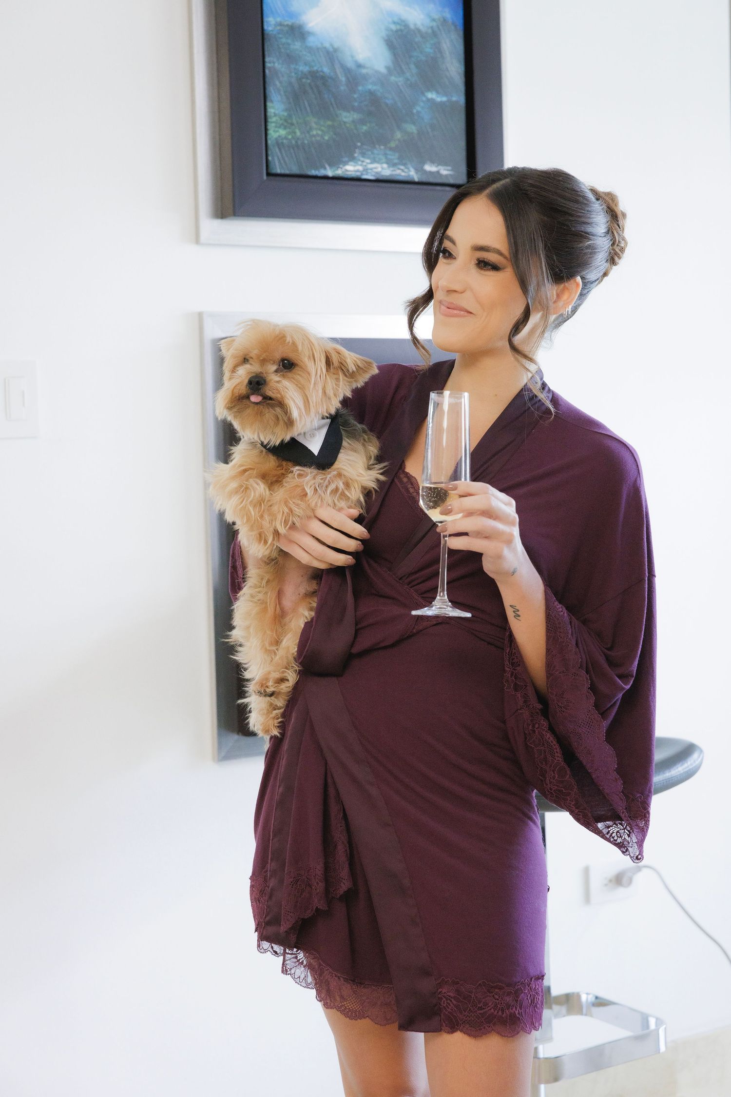 Getting ready in burgundy robes with a small dog while holding champagne glasses in an elegant setting.