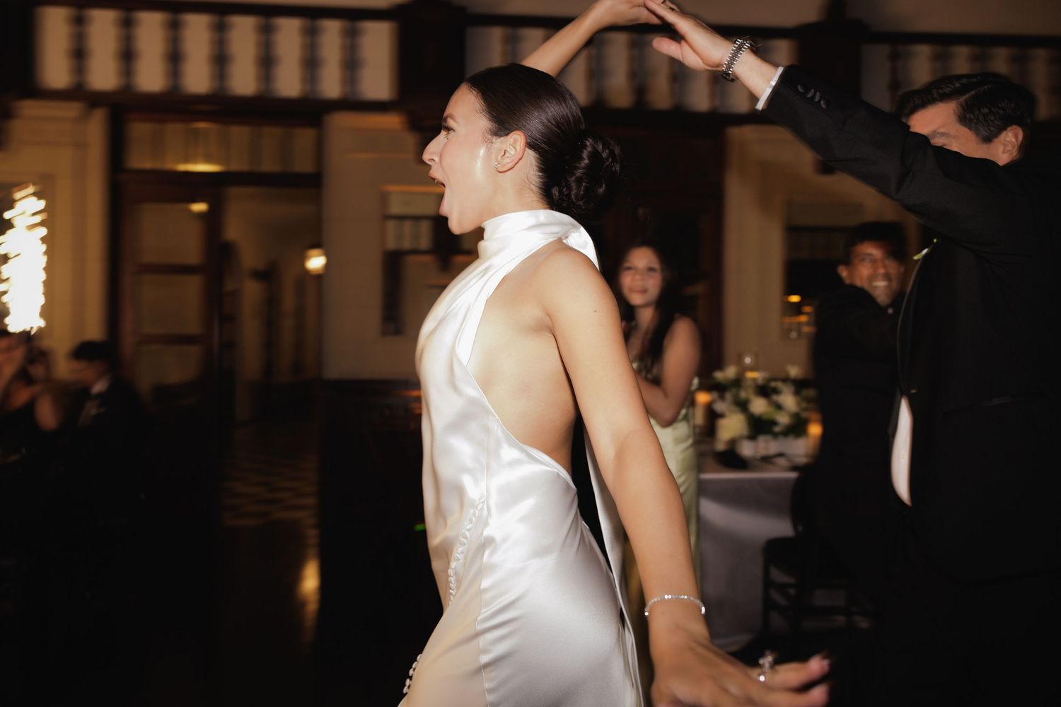 A couple shares a romantic dance at a wedding reception in a dimly lit ballroom.