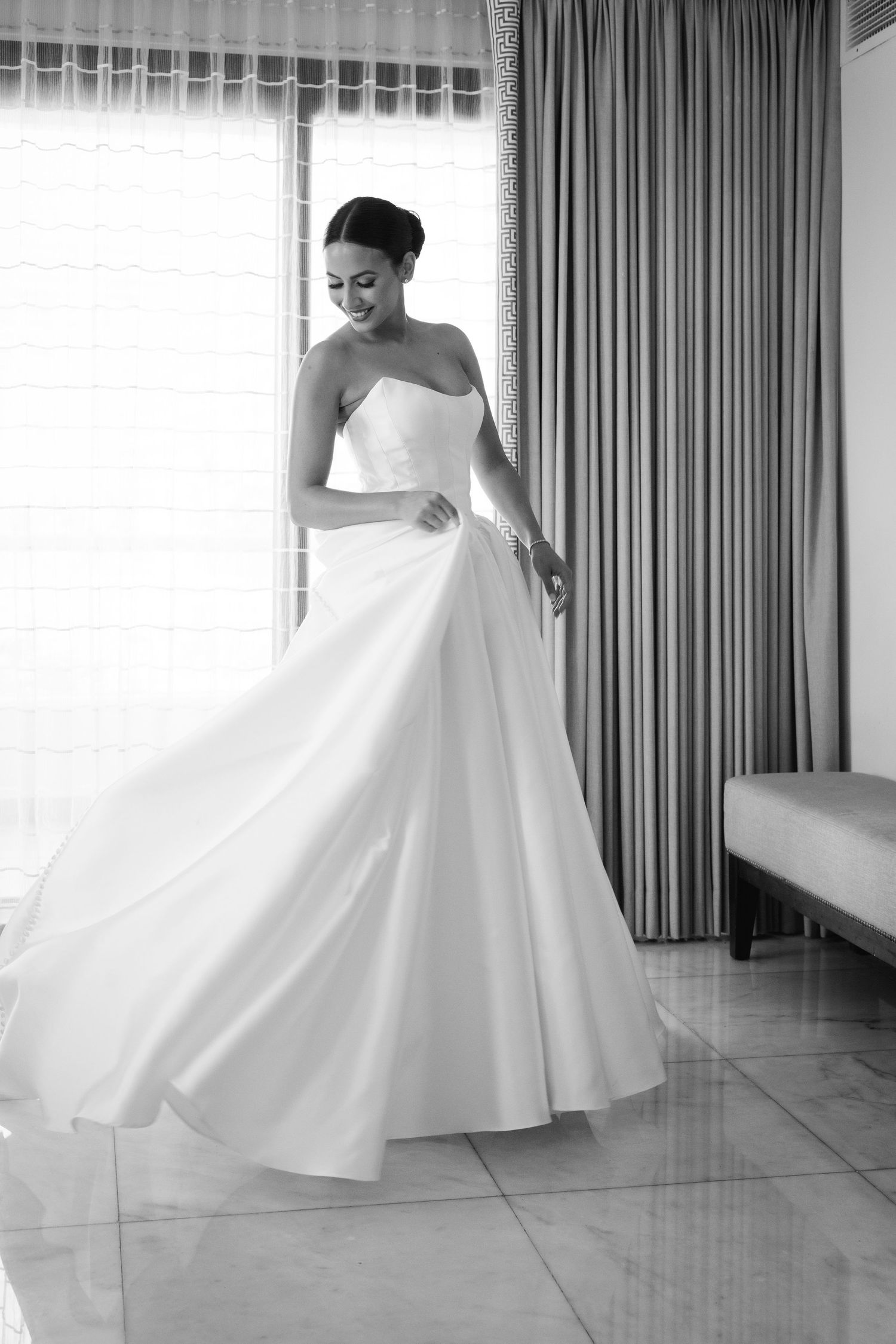 Black and white portrait of bride twirling in classic ballgown style wedding dress.