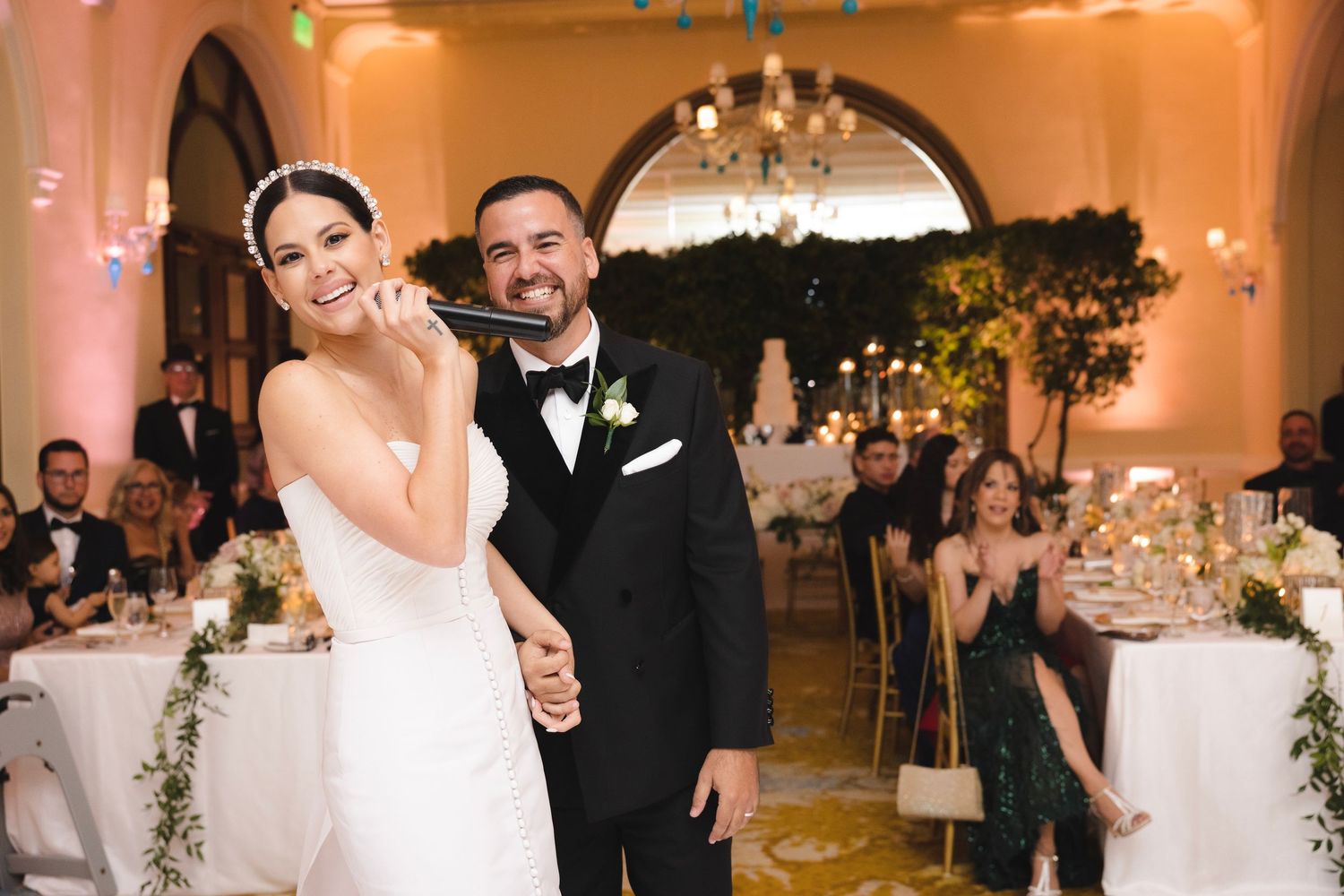 Joyful couple enjoying their first dance together at an elegant wedding reception with chandeliers and decor.