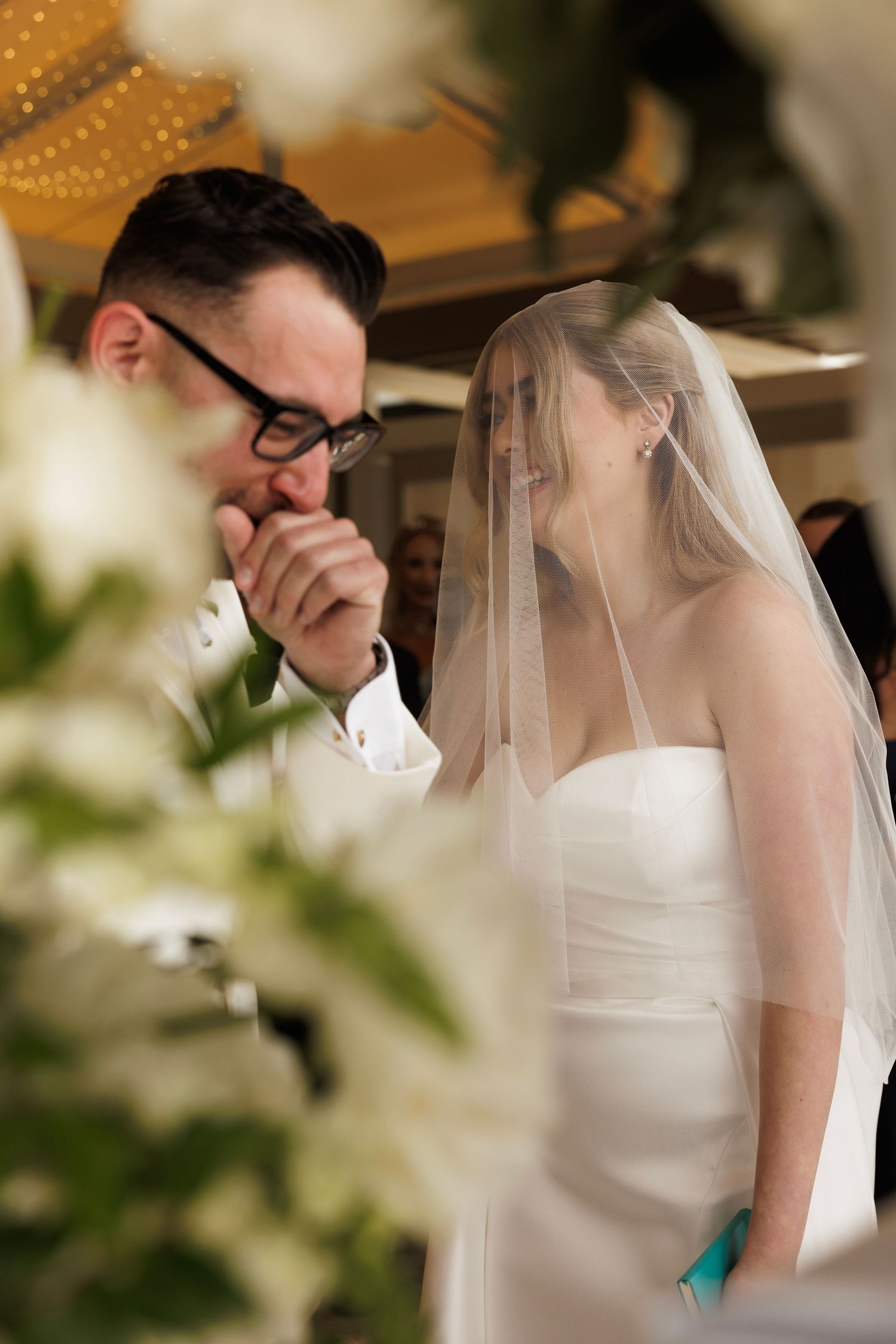 A couple shares an intimate moment during their wedding ceremony with soft lighting and floral decor.