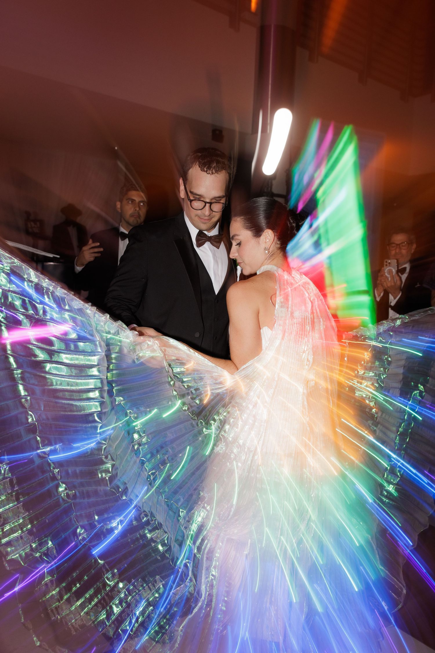 Wedding couple dancing with stunning rainbow light trails creating a magical effect on the dance floor.