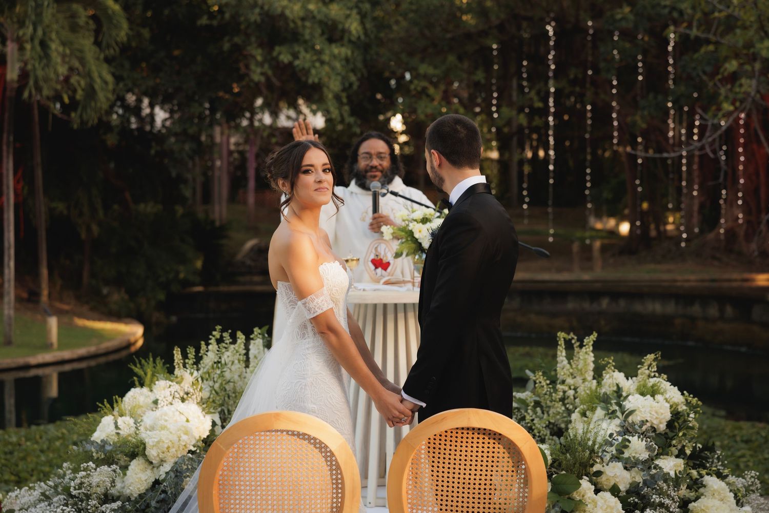 Elegant outdoor wedding ceremony with white floral arrangements and string lights creating a romantic ambiance.