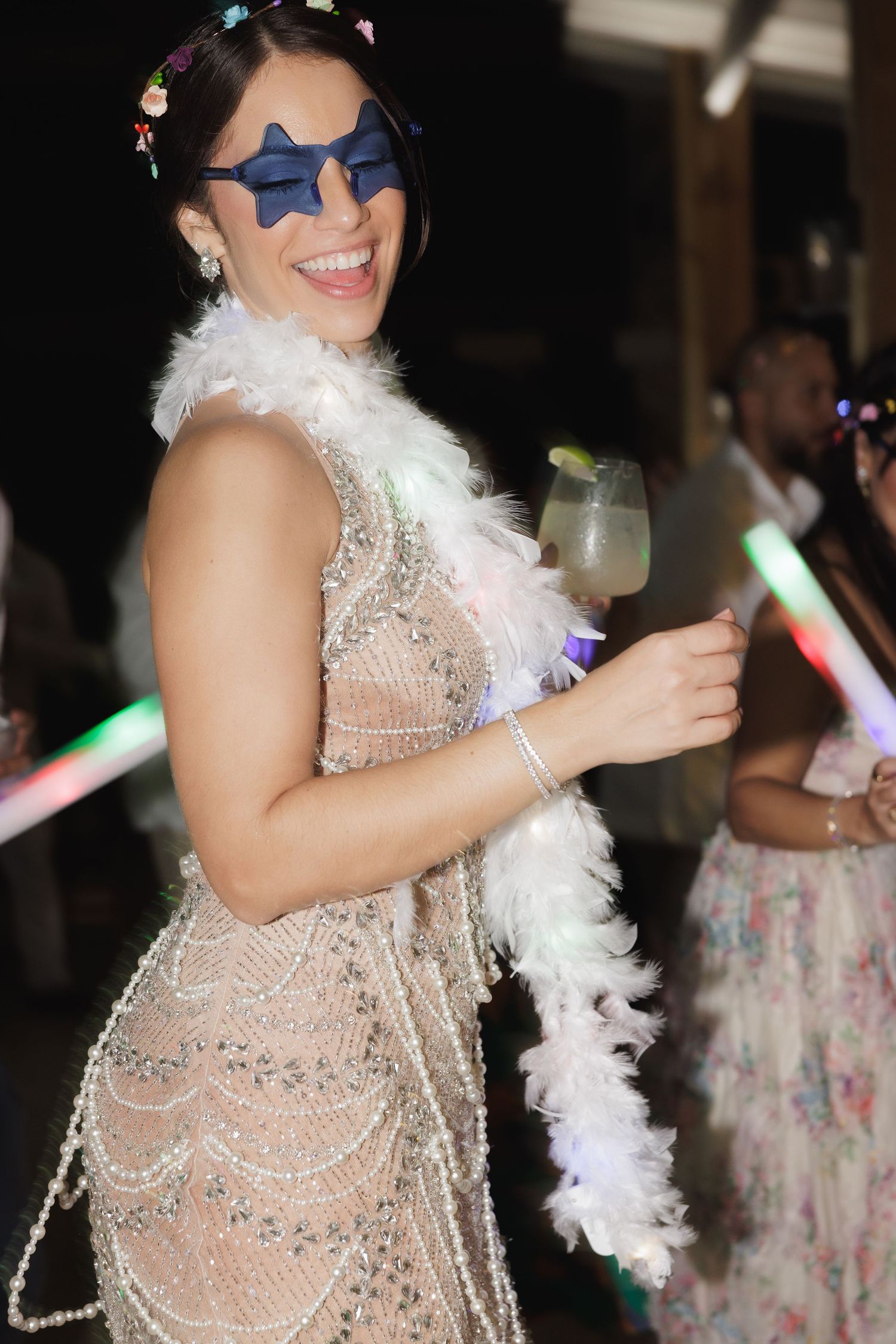 Partygoer in a beaded vintage-style dress and feather boa enjoys a celebration.