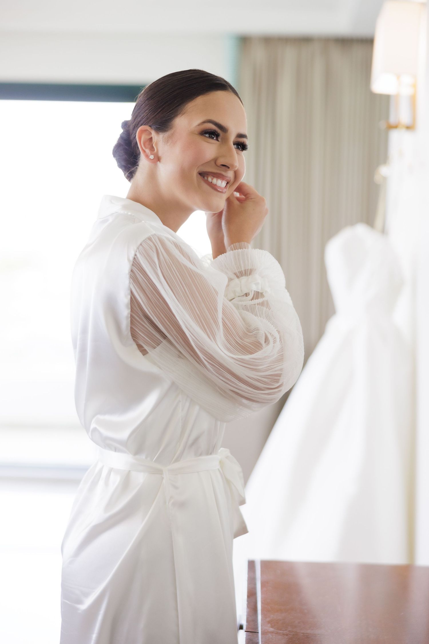 Getting ready moments captured in soft window light with white robes.
