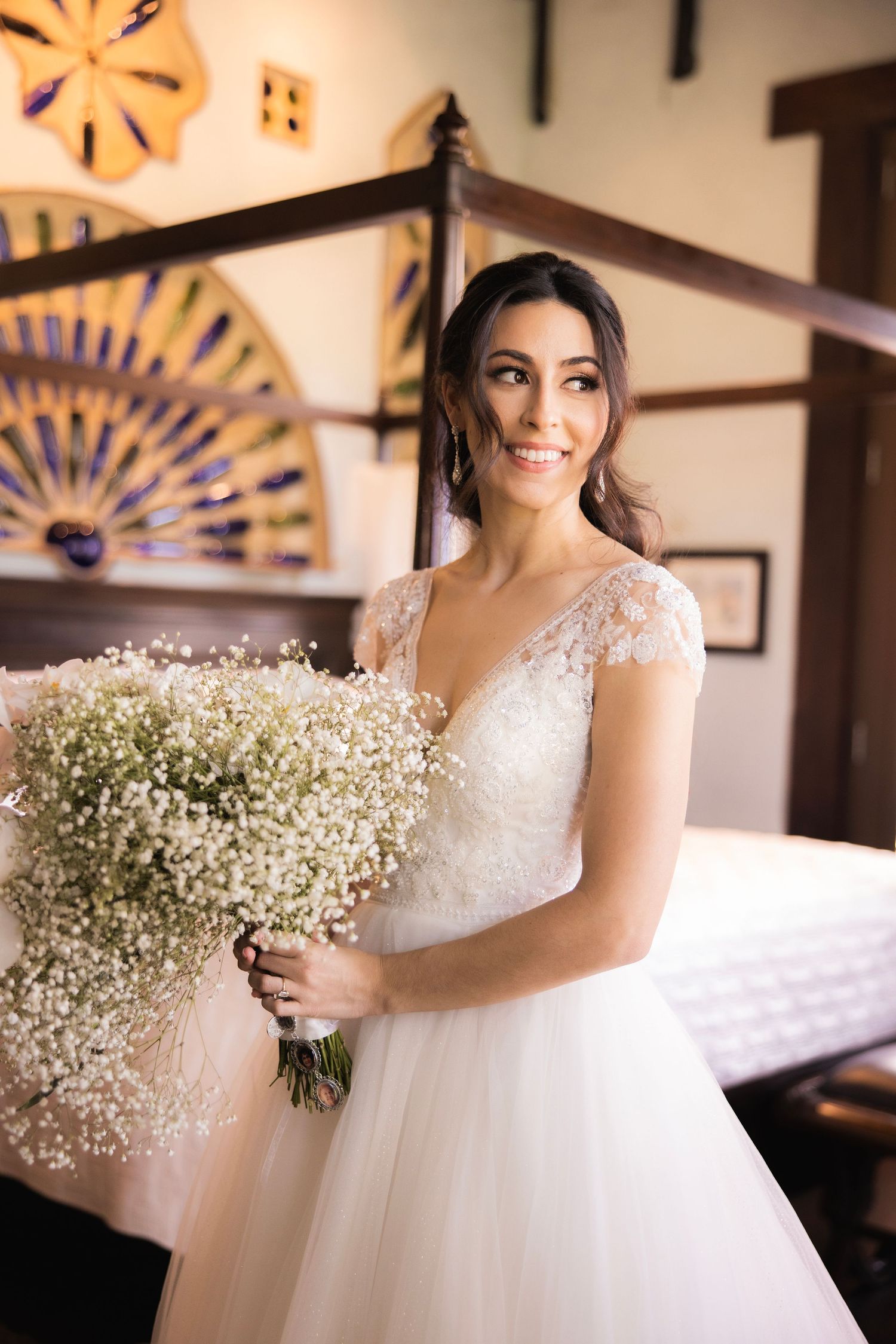Beautiful wedding dress with delicate lace details and baby's breath bouquet in warm lighting.