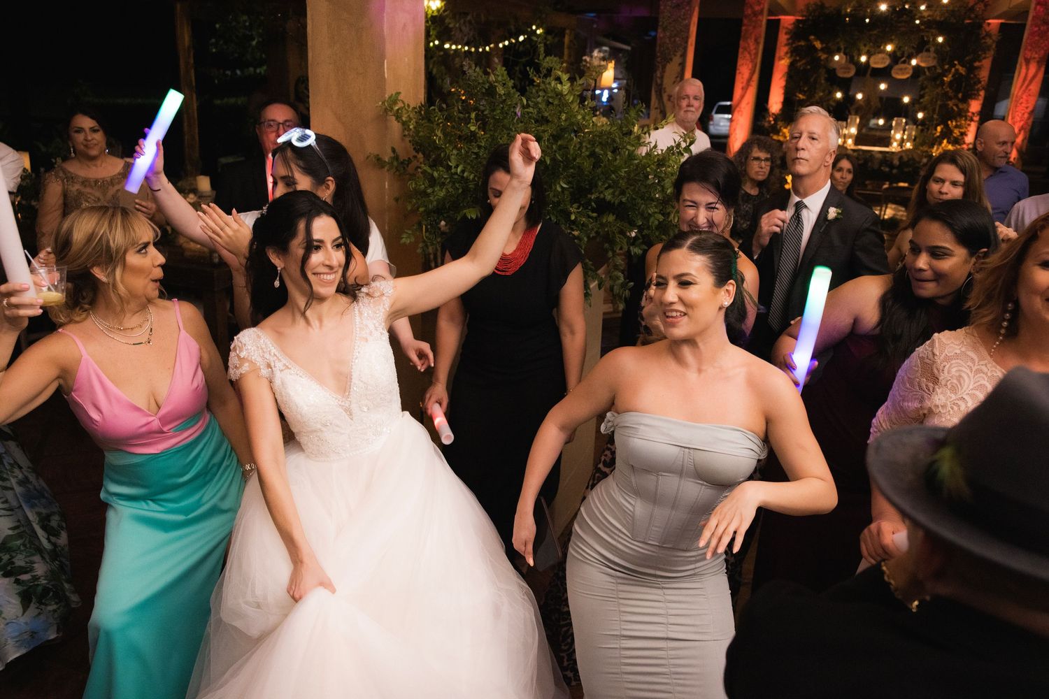 Wedding guests dancing together on the dance floor during evening reception celebration under string lights.