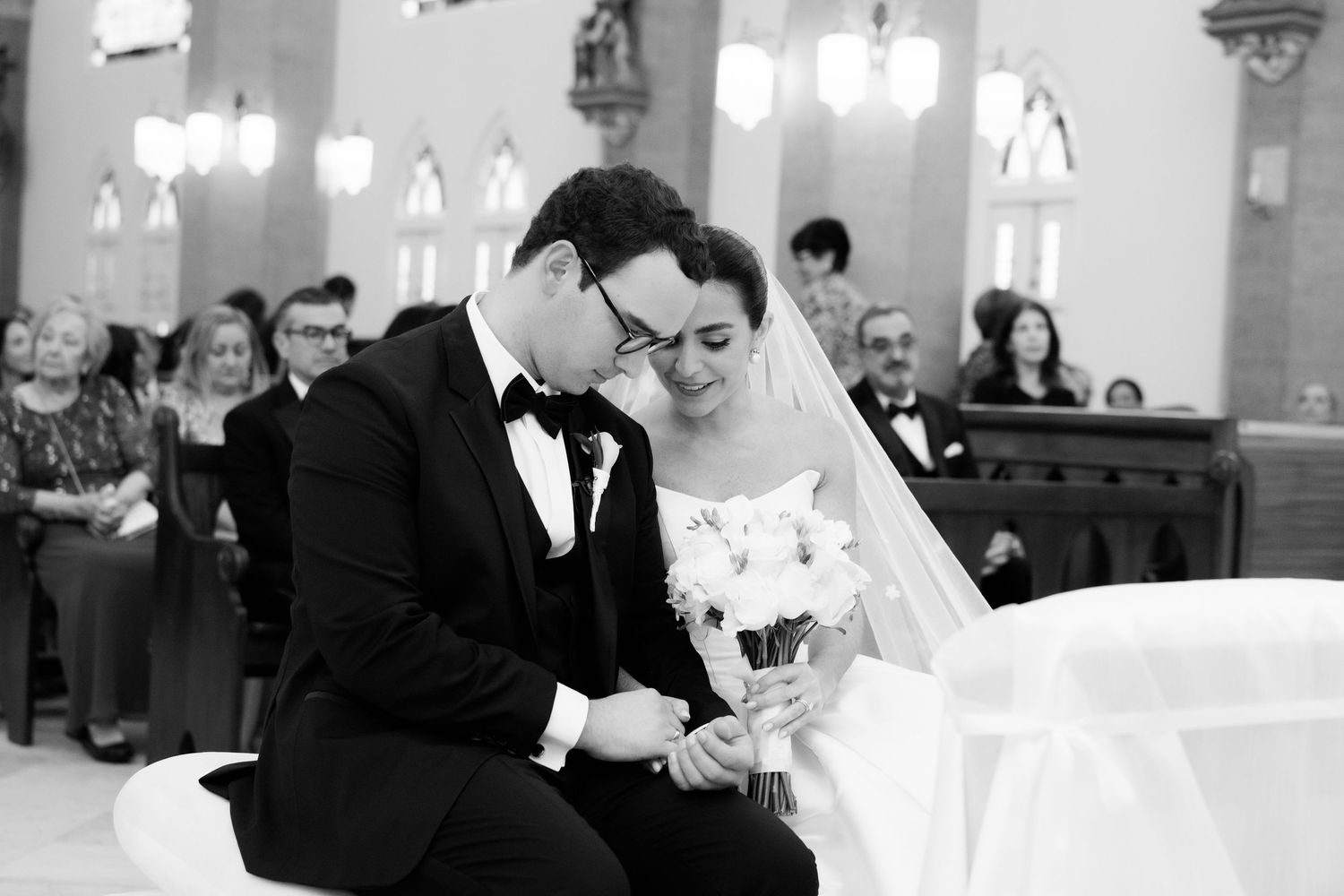 Black and white photo of a wedding ceremony in a church with elegant lighting and architecture.