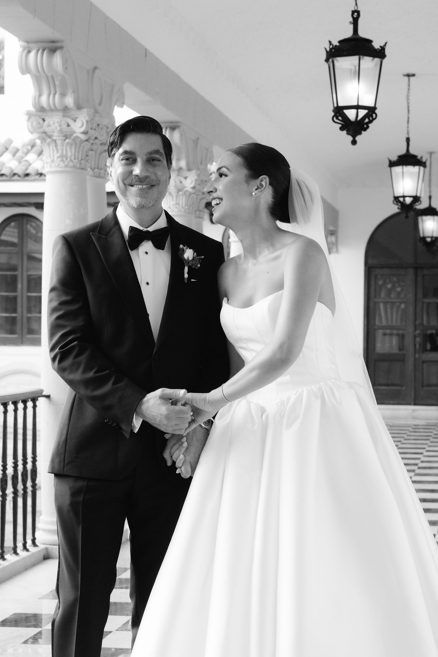Black and white wedding photos showing elegant moments in a grand hallway.