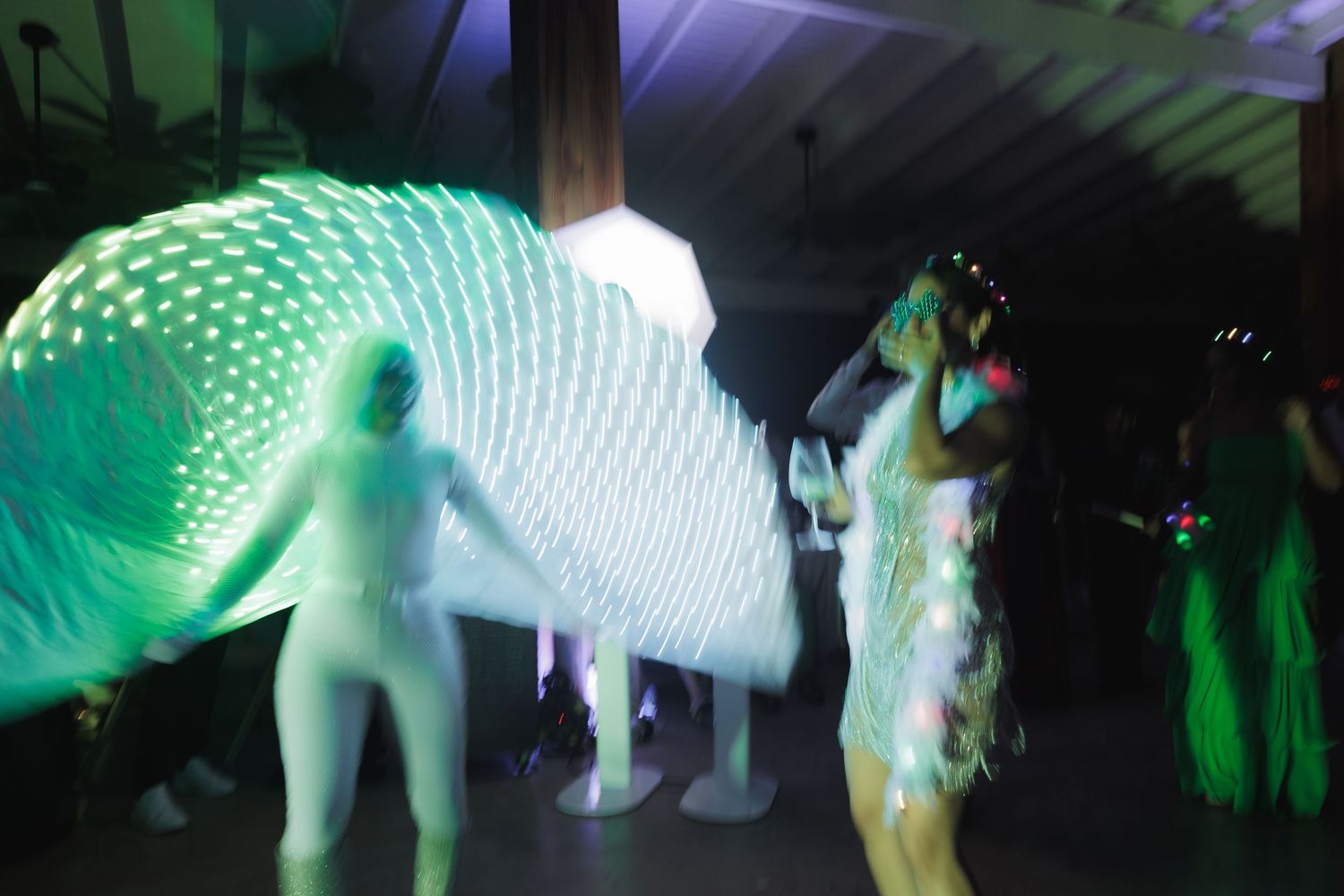 Glowing green light effects create ethereal patterns during a dance party.