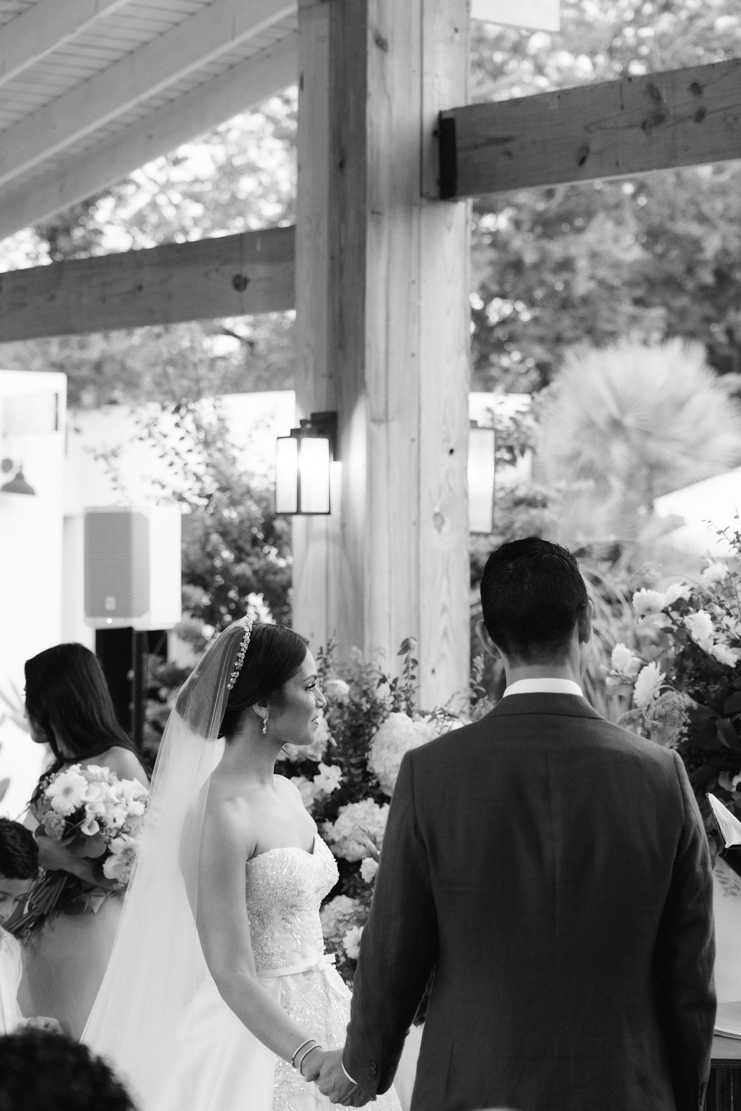 A wedding ceremony processional with bridesmaids and groomsmen walking down an outdoor covered walkway.