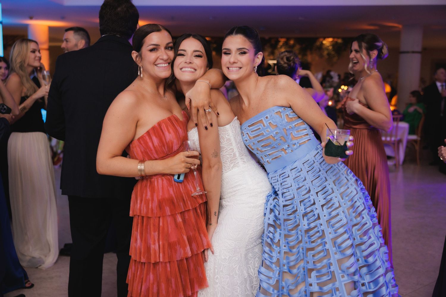 Wedding party members in coral and blue dresses posing together at an elegant reception.