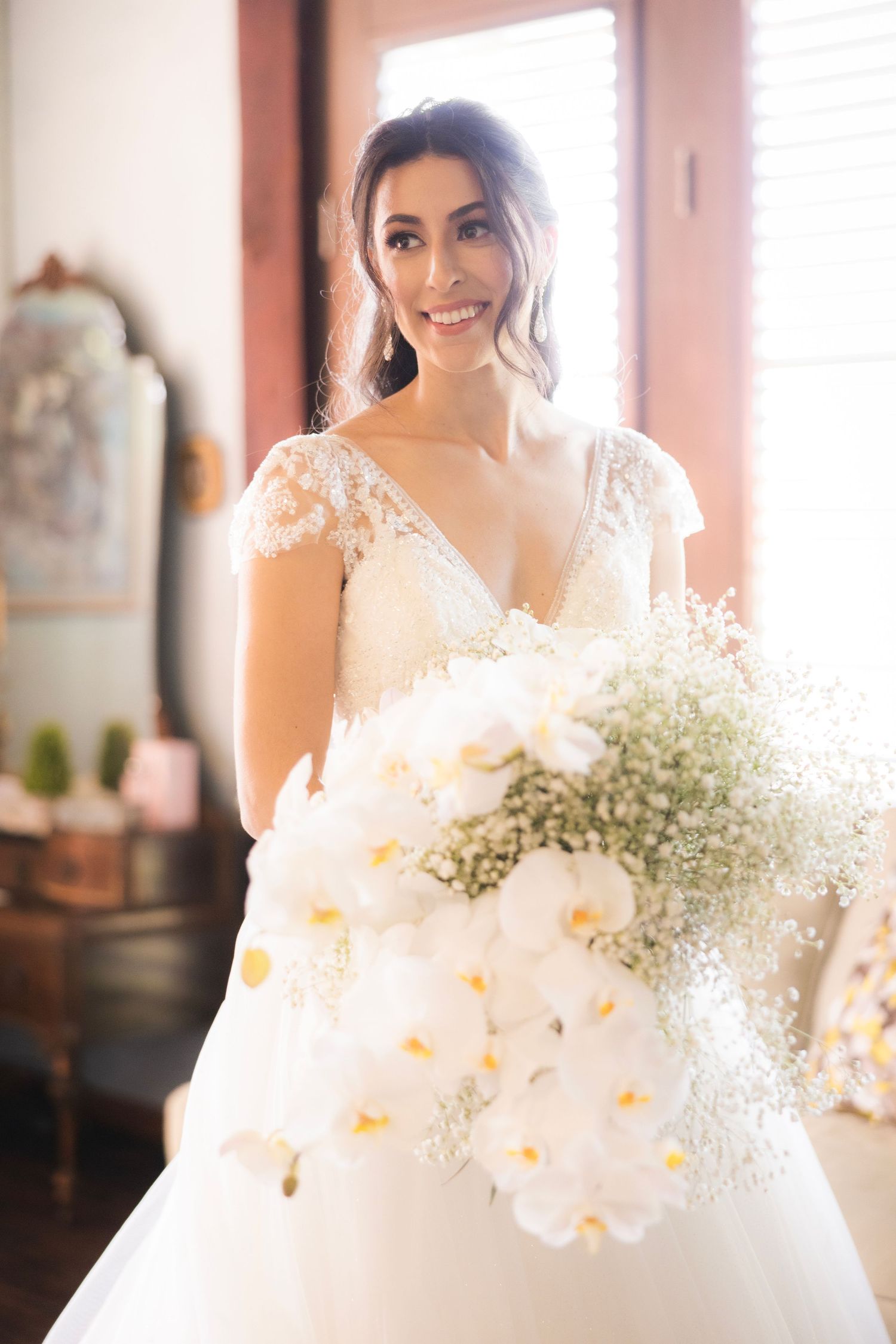 Beautiful bridal bouquet featuring white orchids and baby's breath in soft natural lighting.
