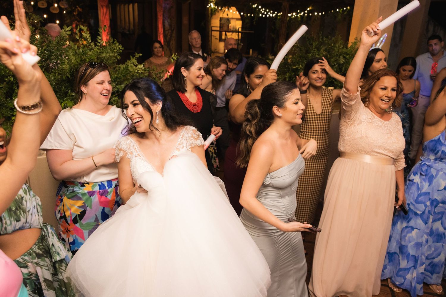 Wedding party celebrating and dancing together in a reception hall with Christmas tree in background.