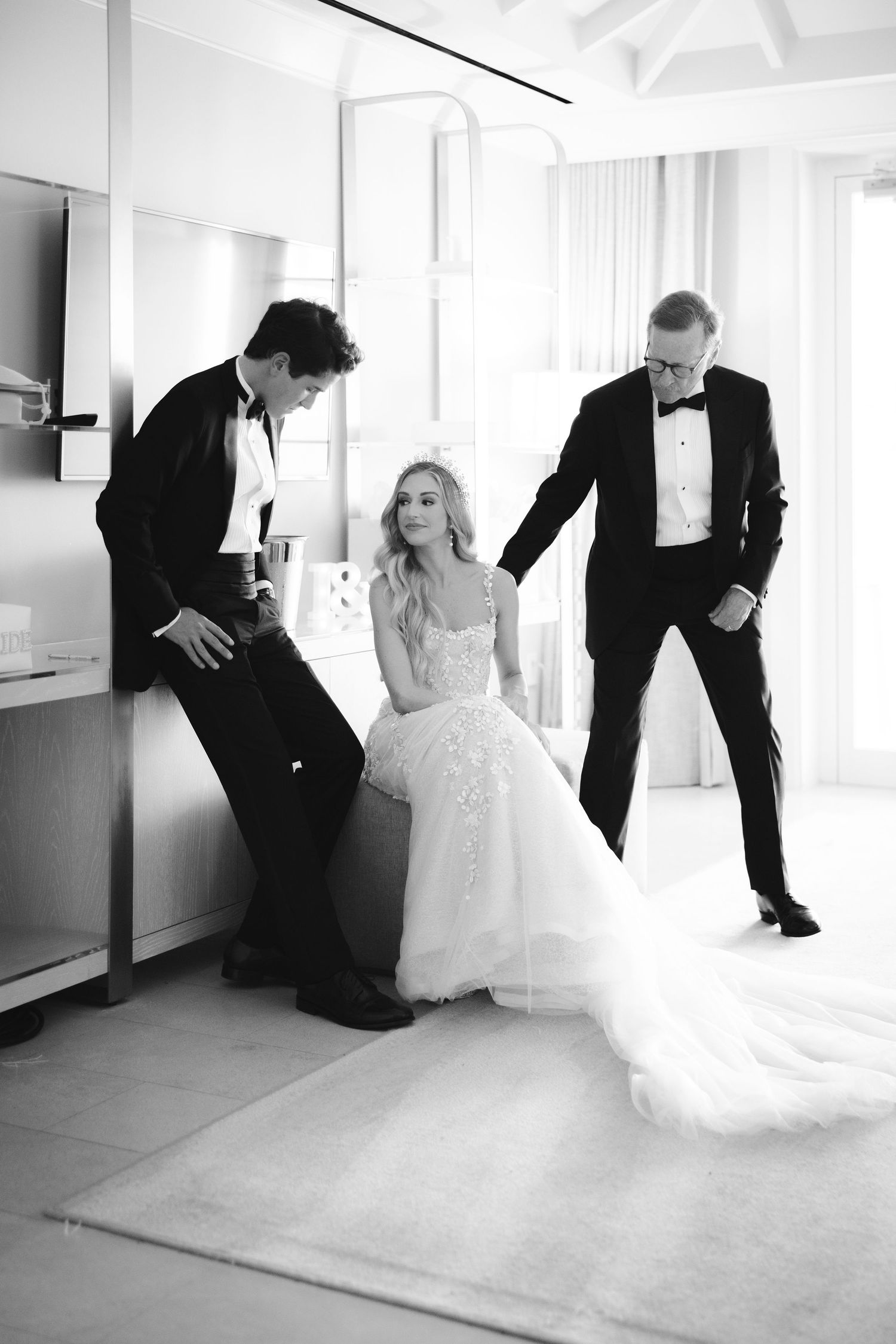 A sequence of playful dance-like movements in black and white showing formal attire against white interior walls.