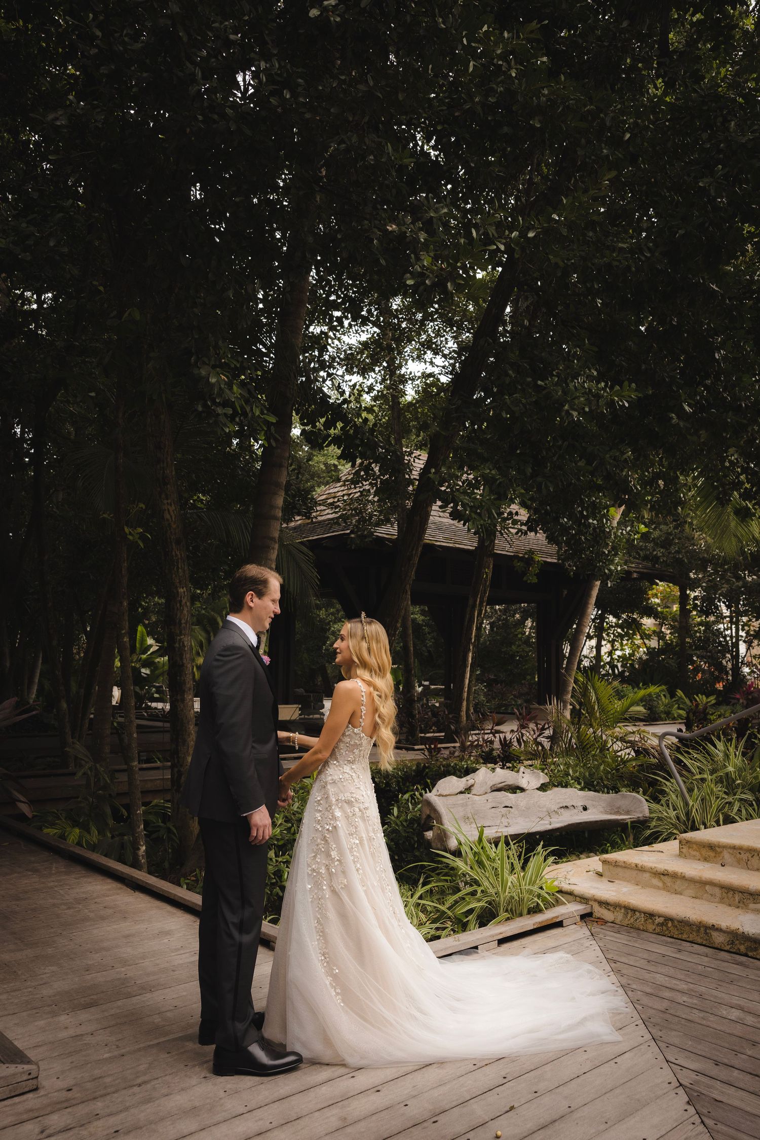 Couple shares romantic moments during their wedding on a wooden deck in a secluded forest setting.