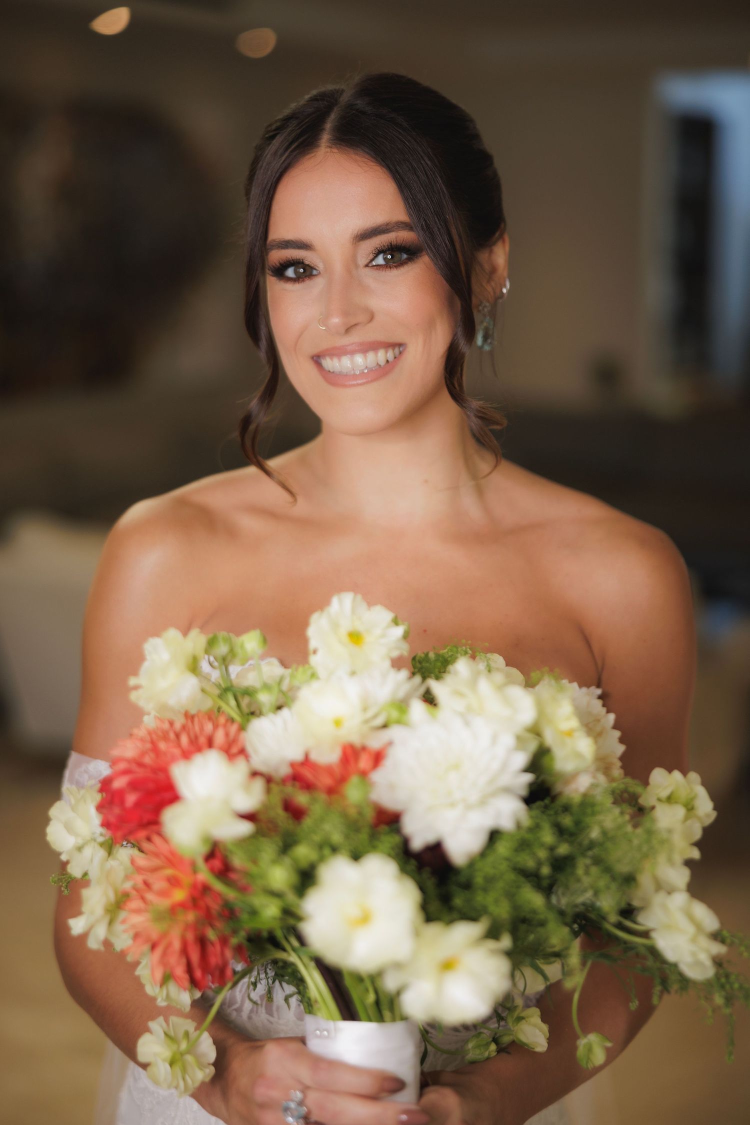 Beautiful floral arrangements featuring white dahlias, coral accents and greenery held at a wedding celebration.