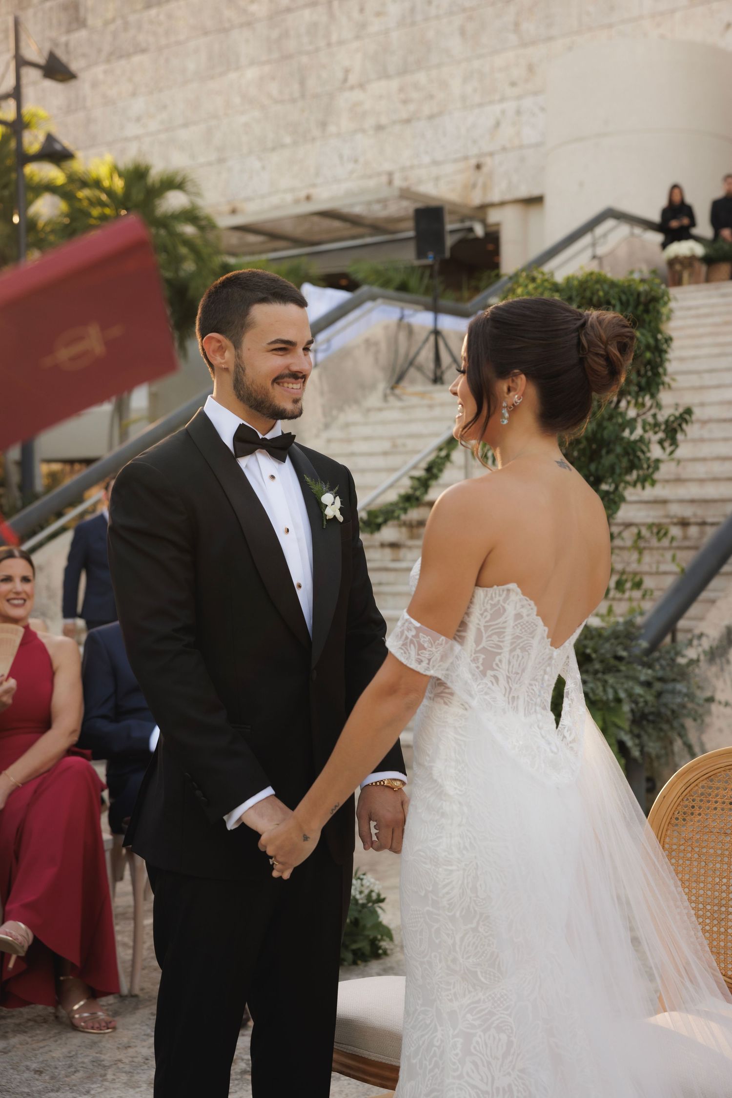 A couple exchanges joyful glances during their outdoor wedding ceremony as they hold hands.