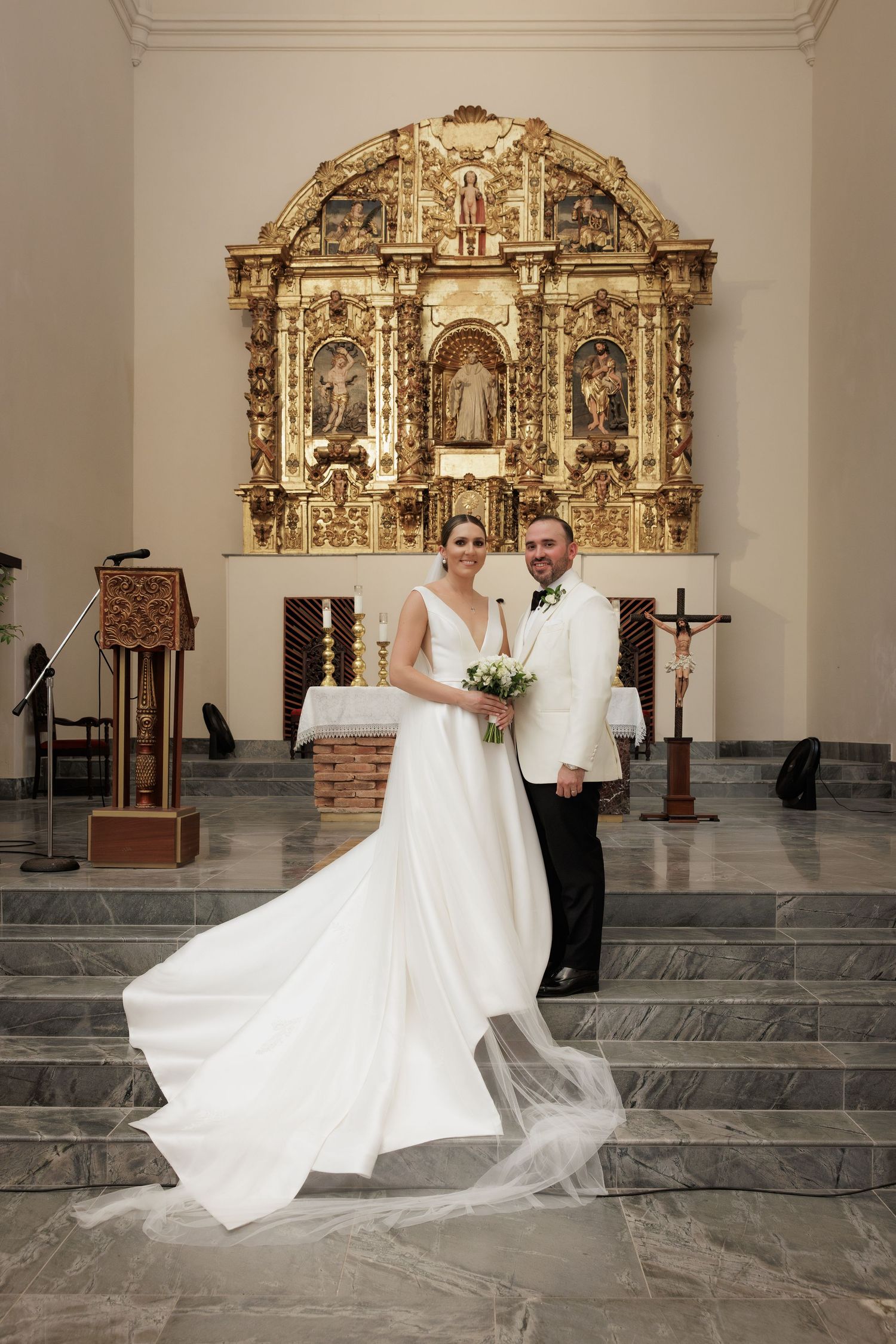 Wedding couple dancing and twirling in front of decorative church altar.