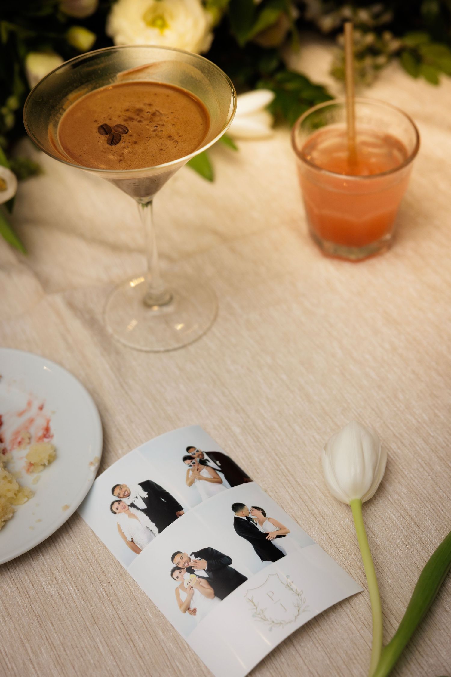 Beverage setup at a wedding with drinks and decorative cards showing illustrations of the couple on a white tablecloth.