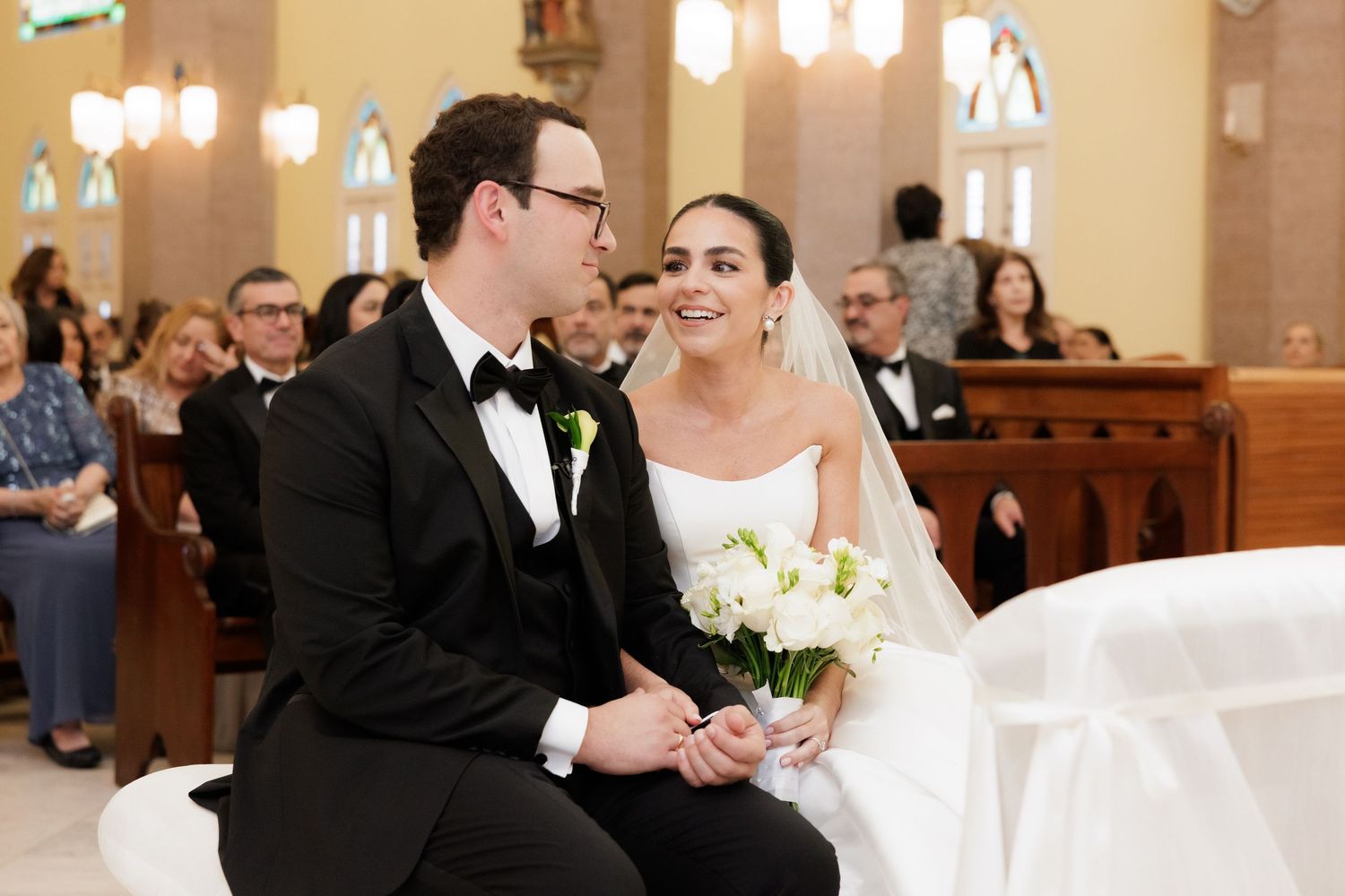 Elegant church wedding ceremony with decorative lighting and wooden pews.
