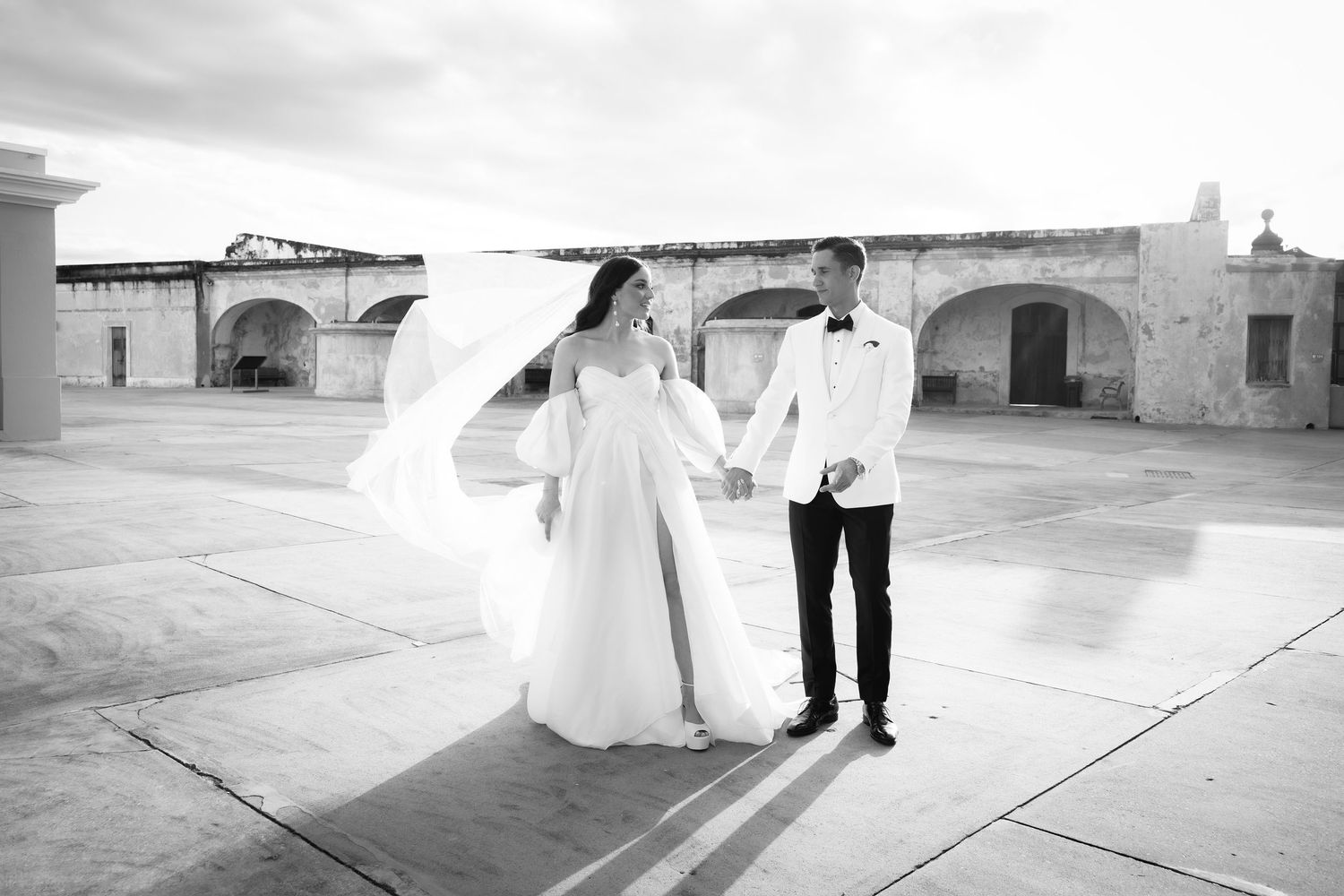Couple takes romantic wedding photos along stone fortress wall path.