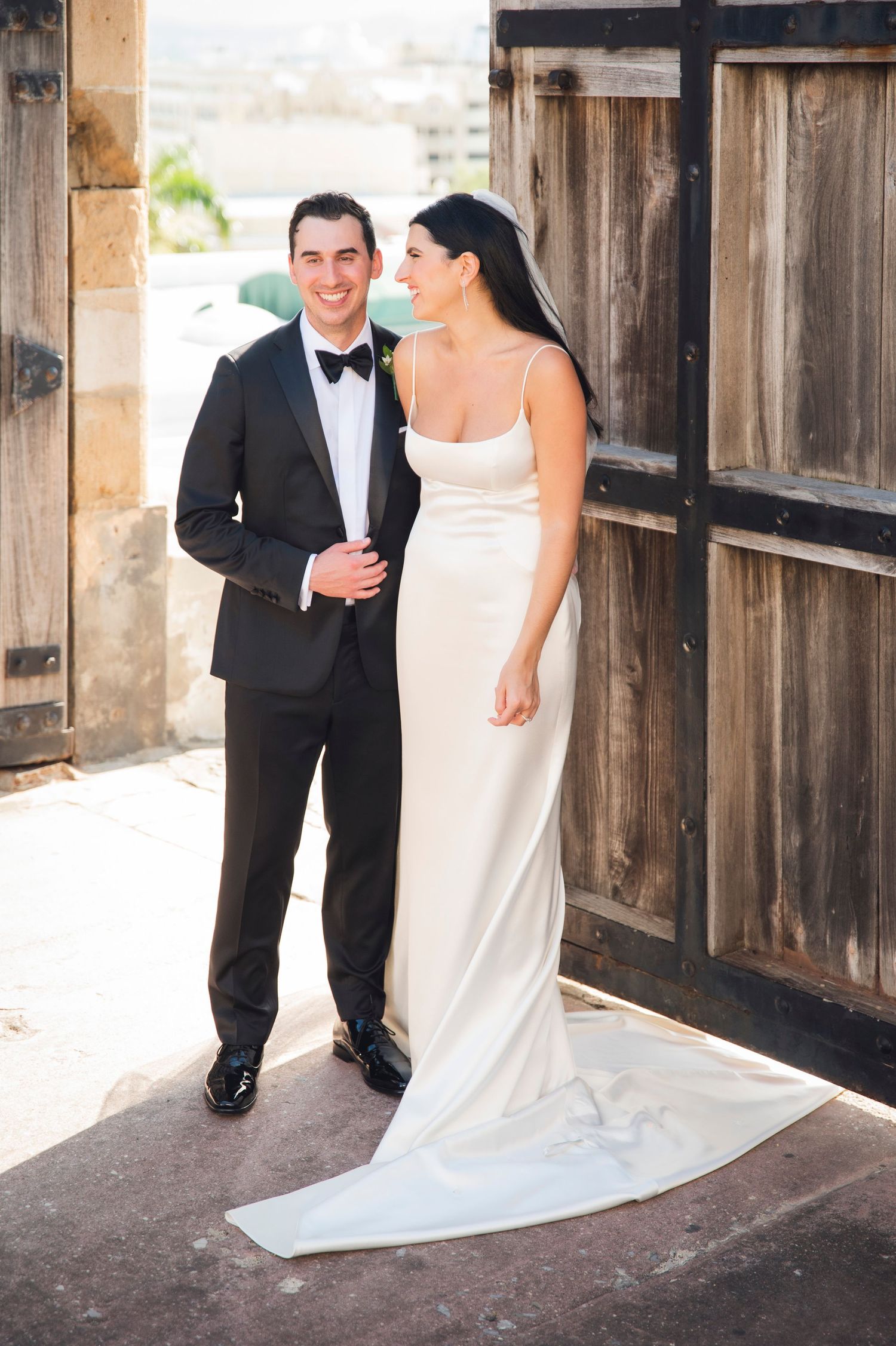 Wedding couple sharing moments in rustic wooden doorway setting.