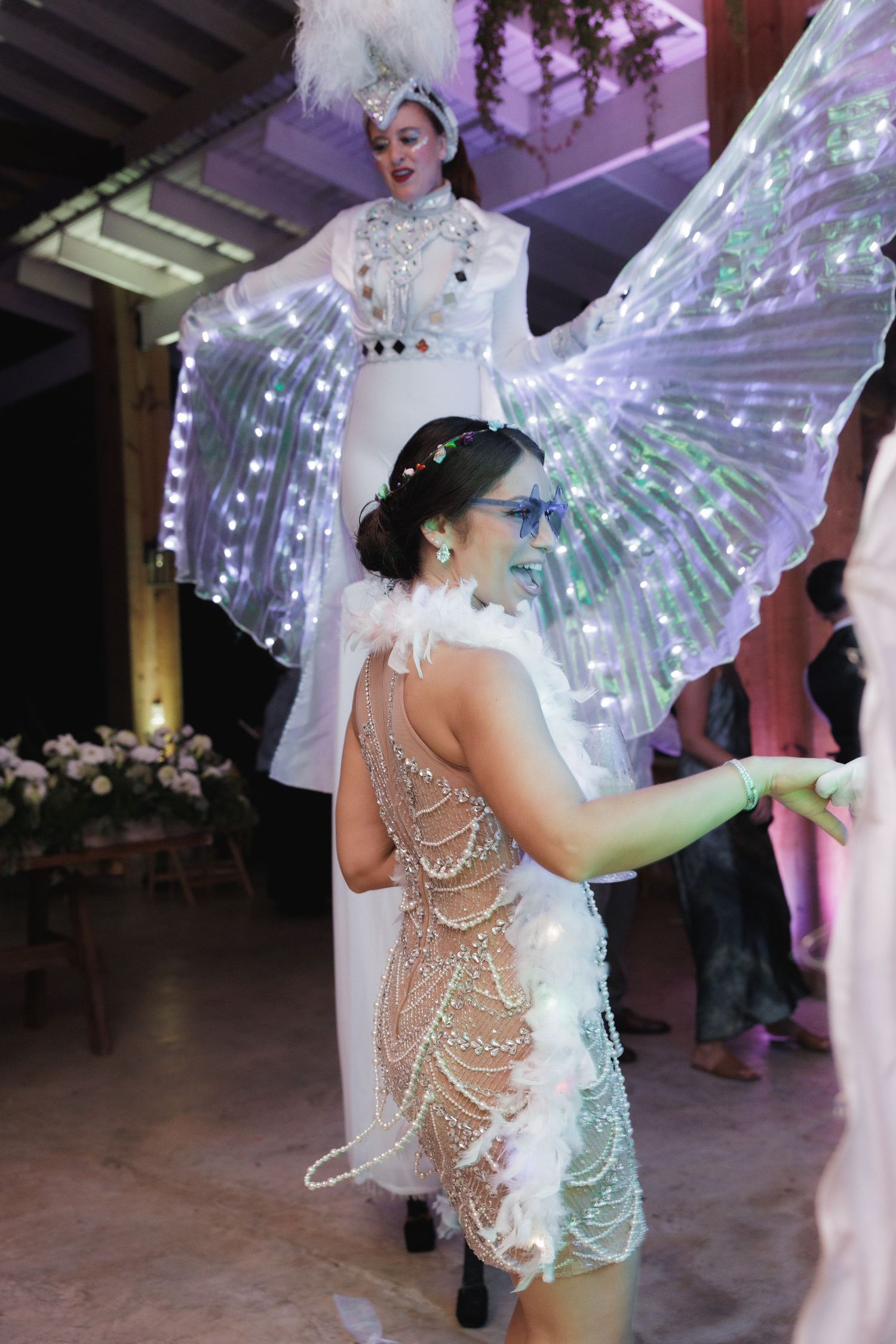 Performer in a glowing LED butterfly wing costume dances under purple stage lighting.