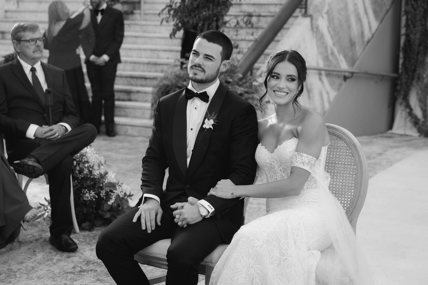 Wedding party shares joyful moments during formal photo session in black and white attire.