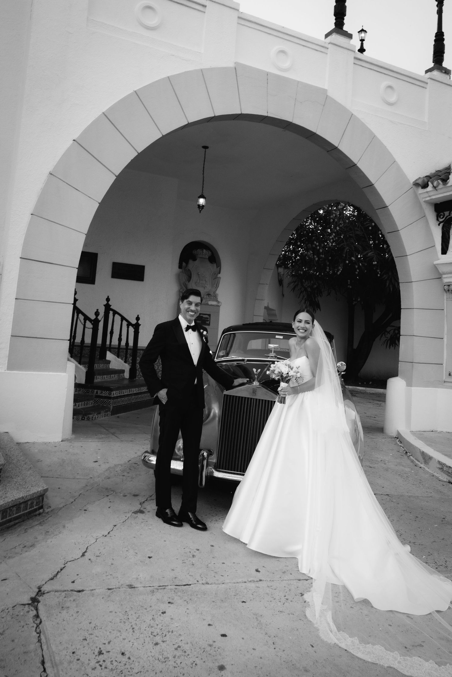 A series of black and white wedding photos showing a couple in formal attire under arched walkways.